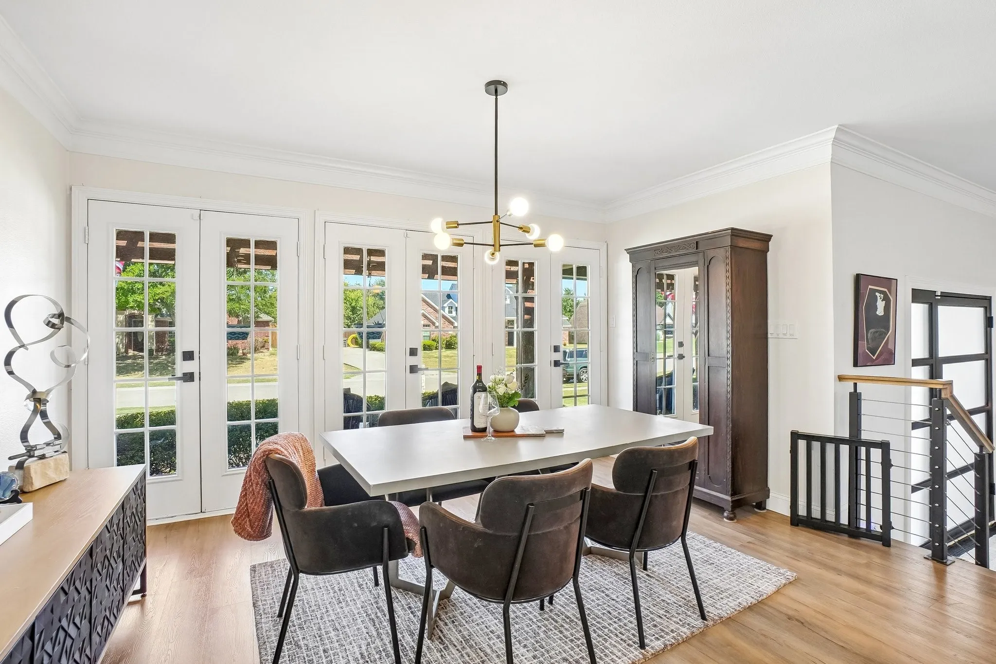 Wood-finish flooring throughout, multiple paneled glass doors with transom windows, and a contemporary chandelier