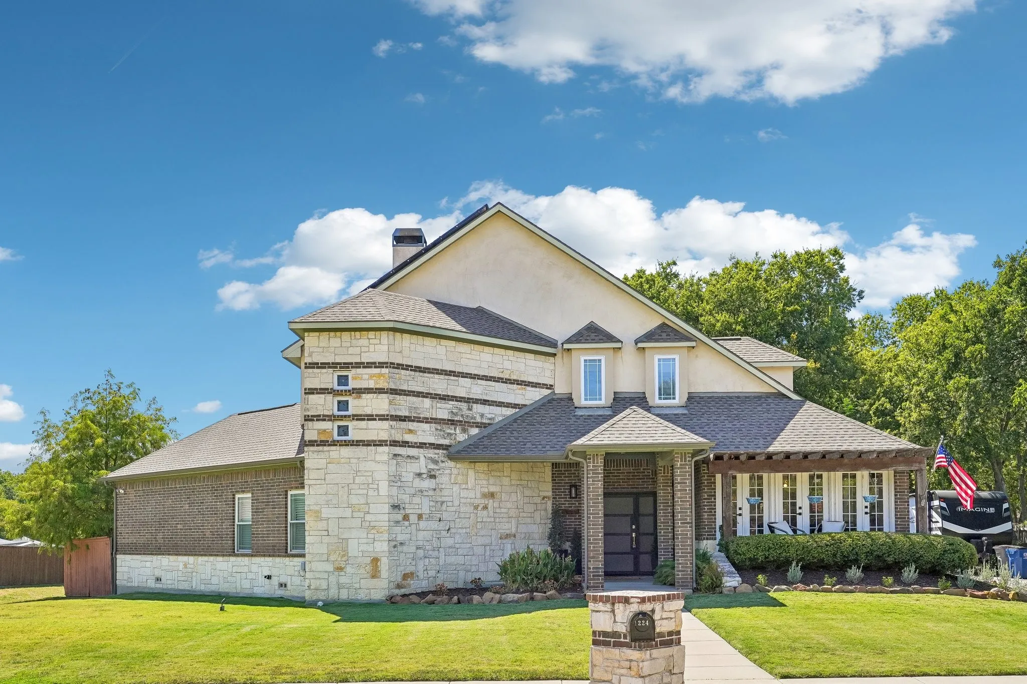 Stone and brick exterior with a covered entry, gabled dormers, and a prominent chimney