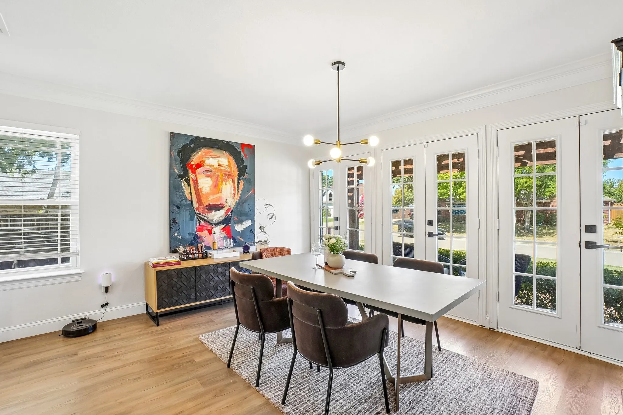 Wood-finish flooring, multiple French doors with transom windows, a modern chandelier, and crown molding
