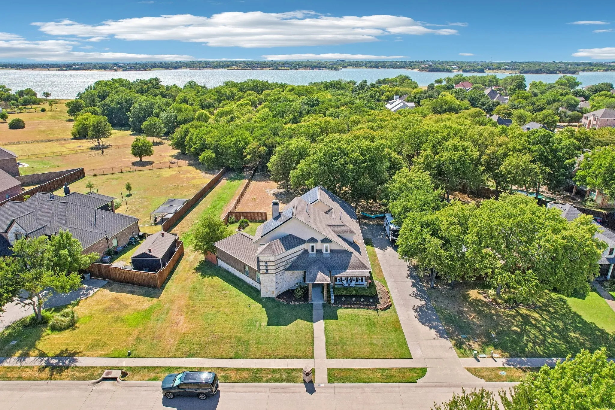 Aerial view showing lake in the background.    Stone and siding exterior with a multi-gabled roofline