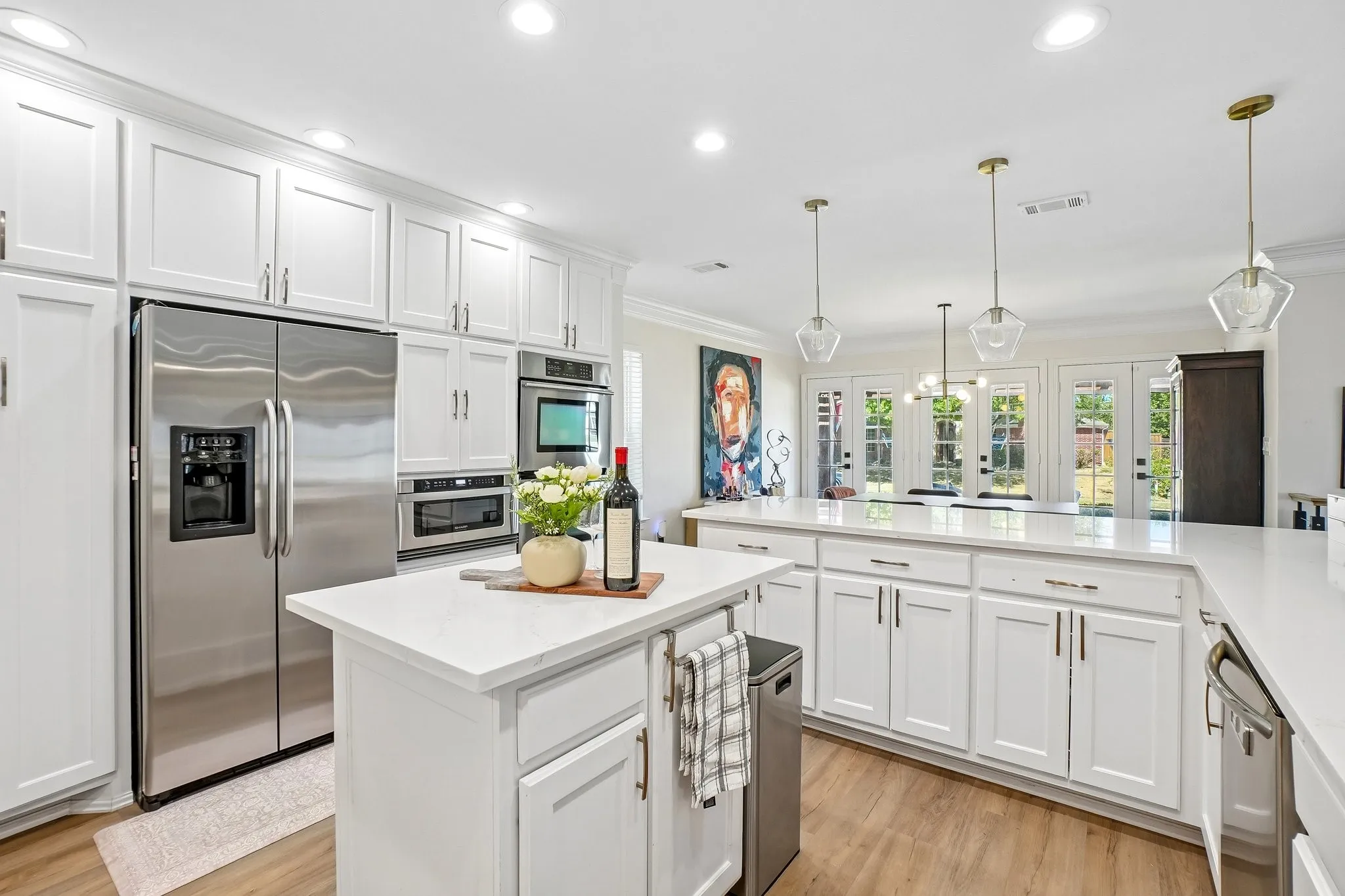 Kitchen featuring white cabinetry, stainless steel appliances, an expansive island with a white countertop, recessed lighting, and wood-finish flooring