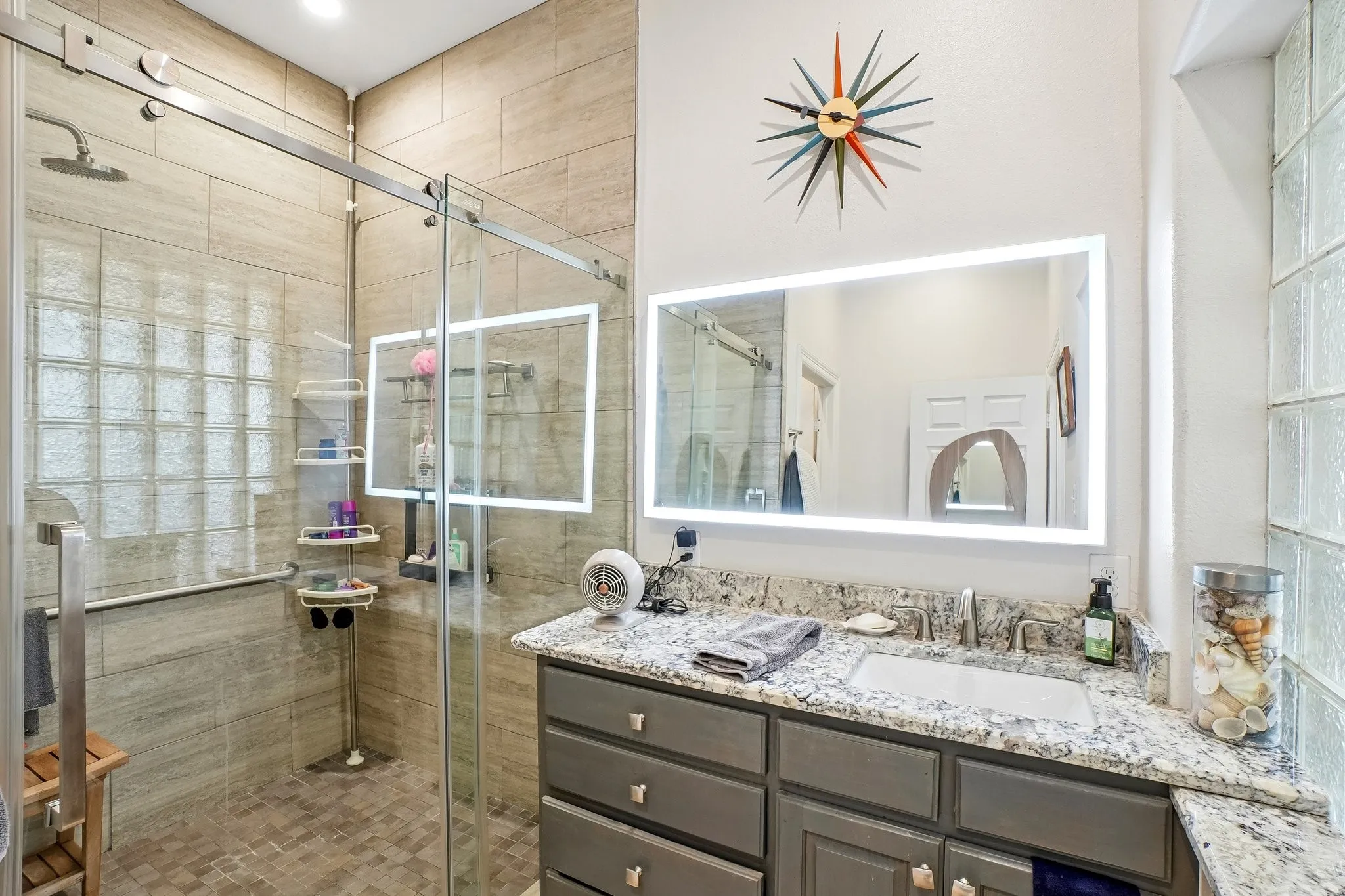 Walk-in shower with glass enclosure, tiled walls, and glass block window