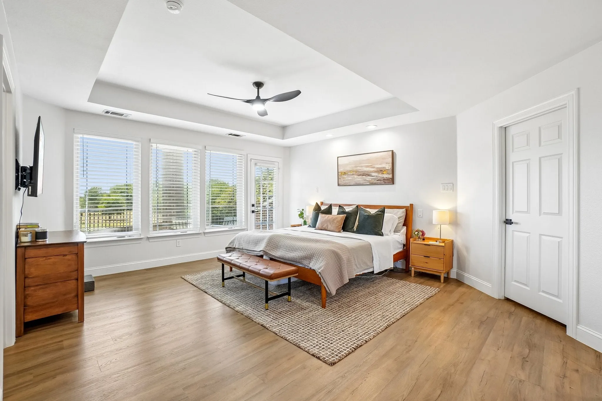 Tray ceiling, wood-finish flooring, multiple windows with blinds, recessed lighting, ceiling fan