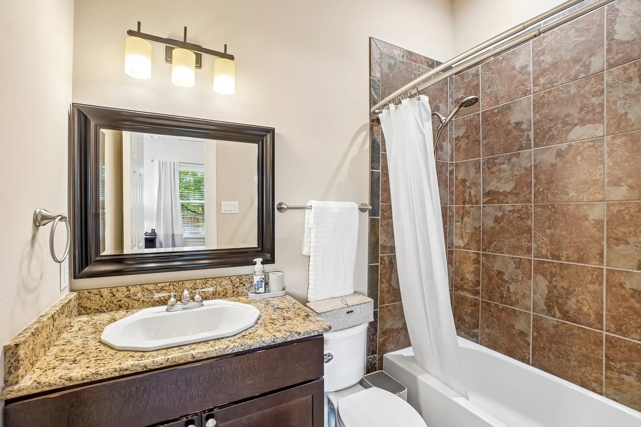 Vanity with granite-style countertop, undermount sink, and dark wood-finish cabinetry