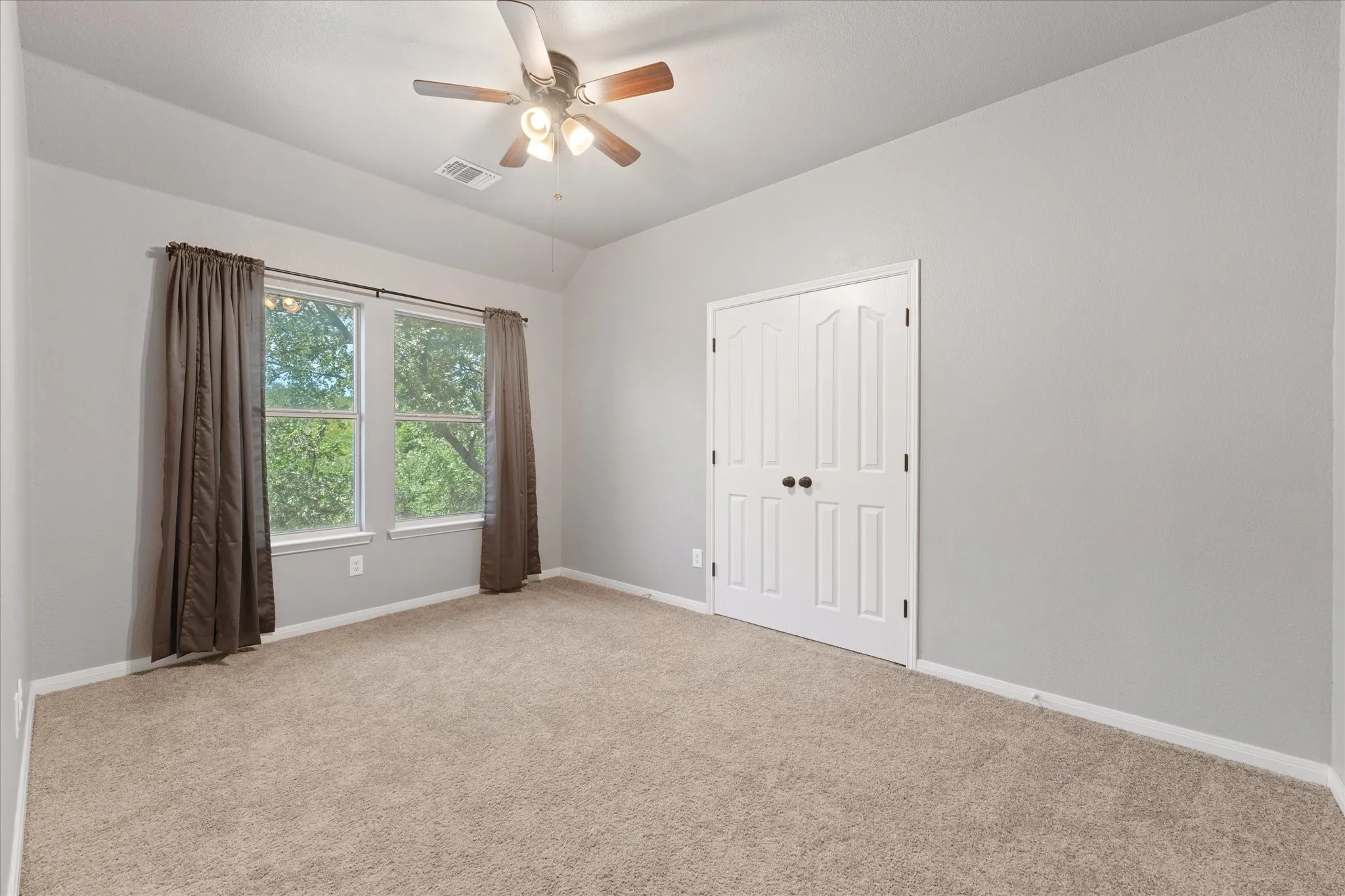 Neutral paint tones, plush carpeting, ceiling fan with integrated lighting, and a double-door closet