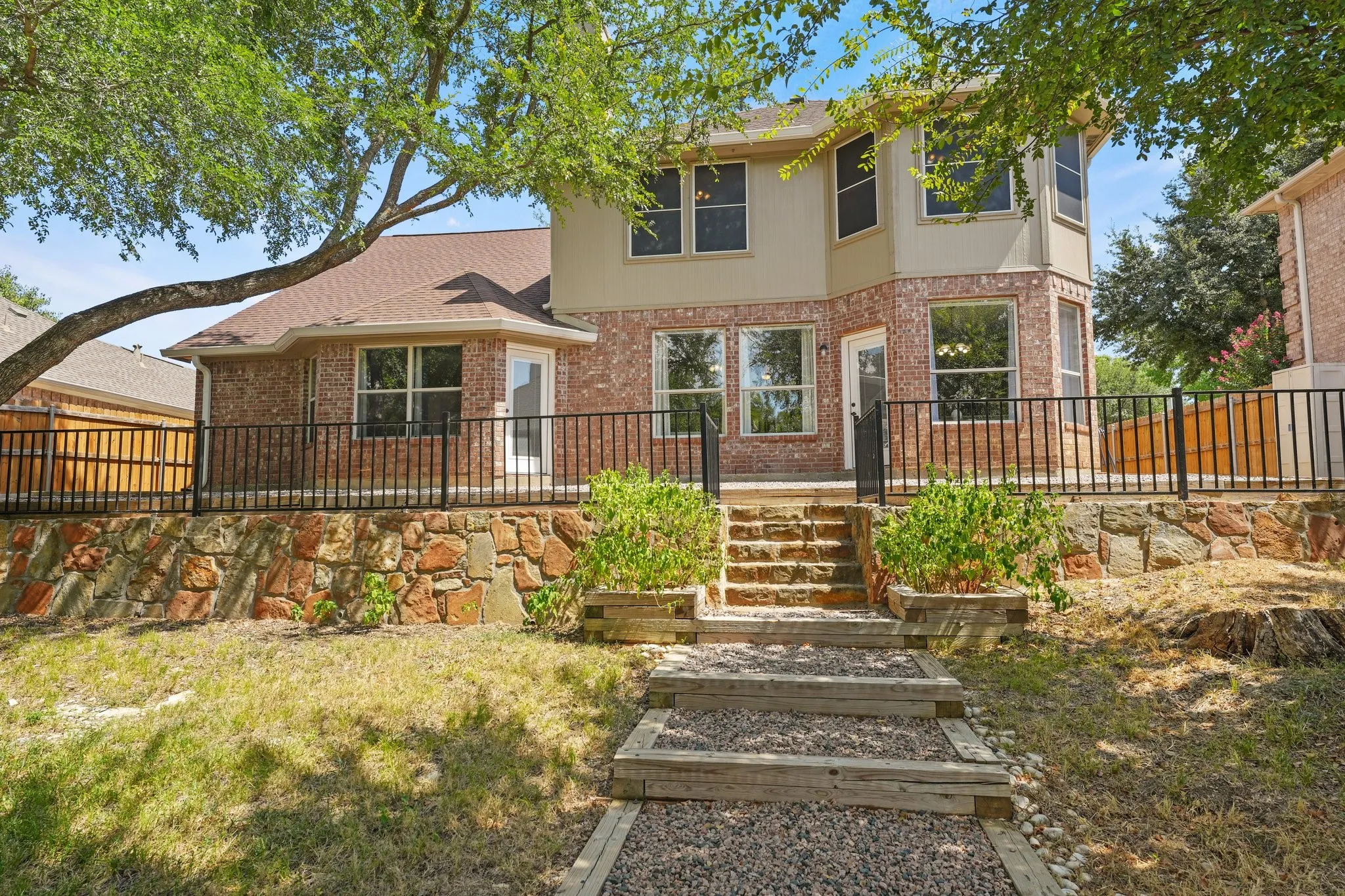 Brick and siding exterior with multiple windows, leading to an elevated deck with black metal railing