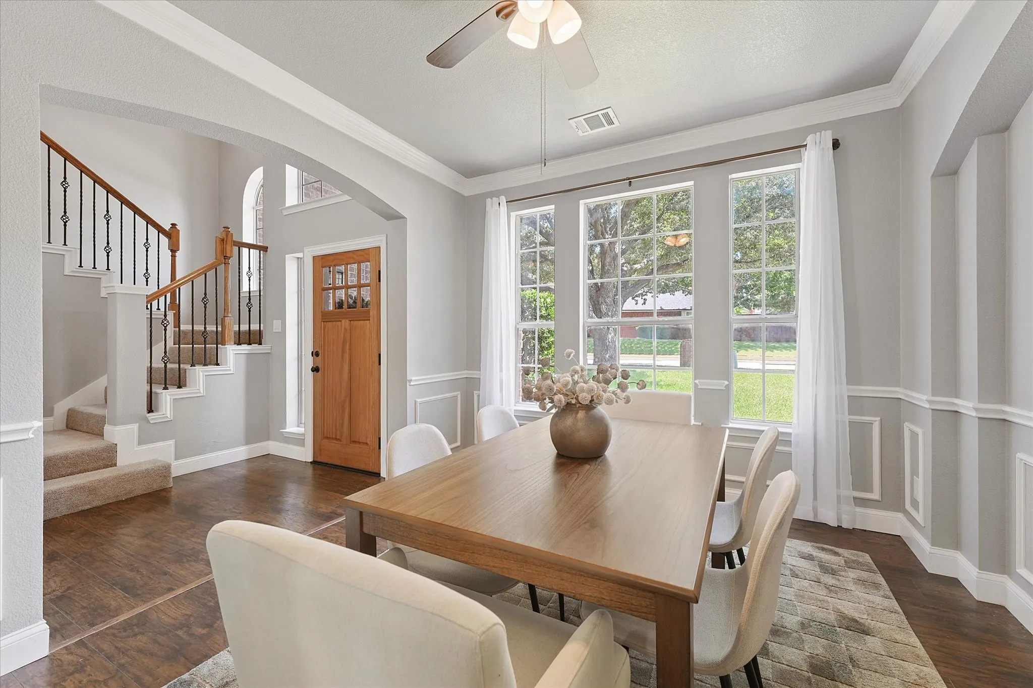 Wood-finish flooring, wainscoting, and large windows with grid patterns