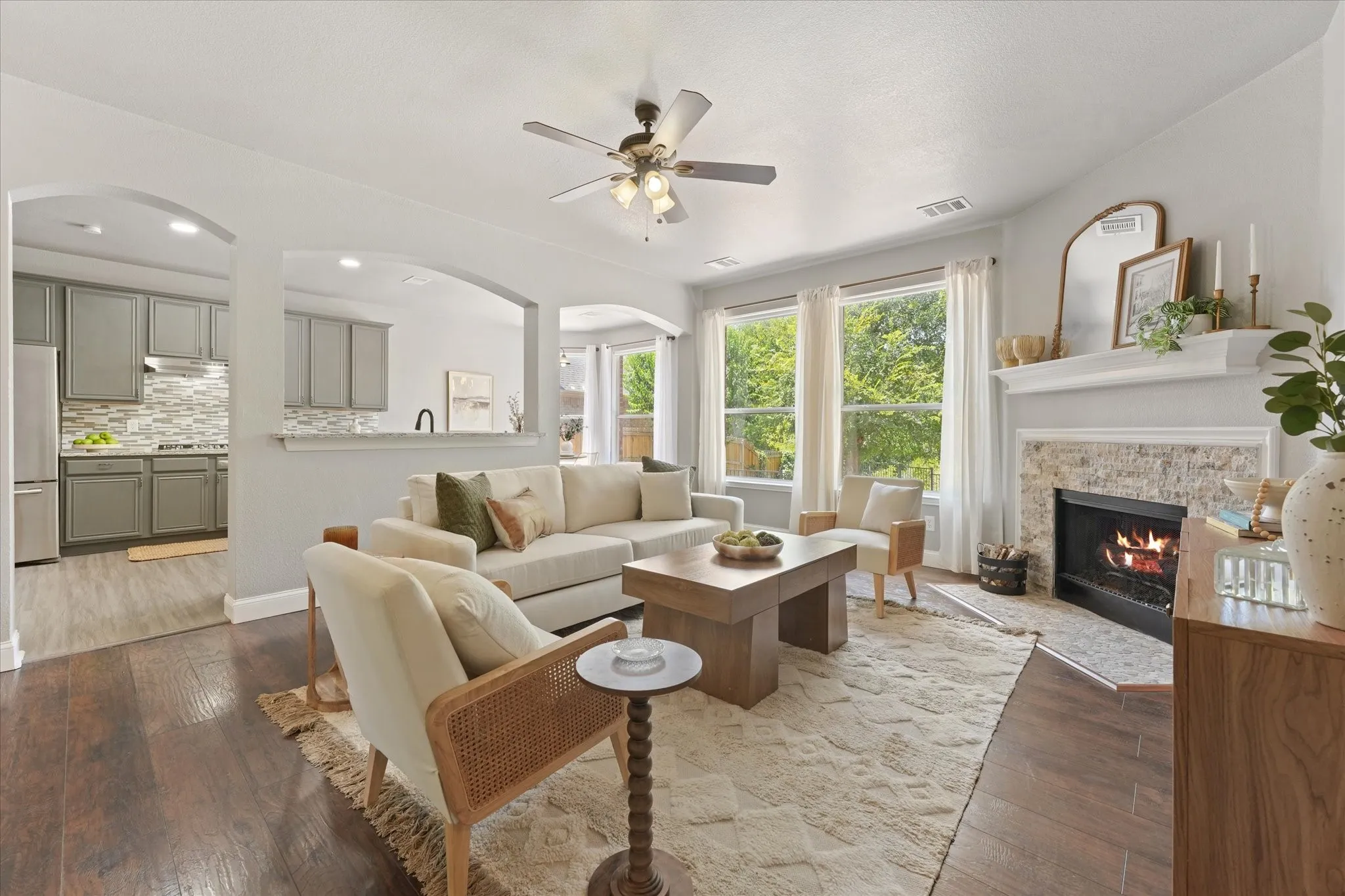 Open-concept living space featuring wood-finish flooring, a ceiling fan, and large windows