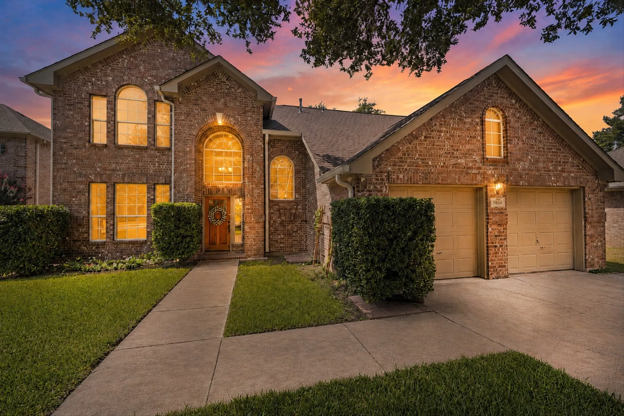Brick facade with arched windows, a two-car garage, and a concrete driveway