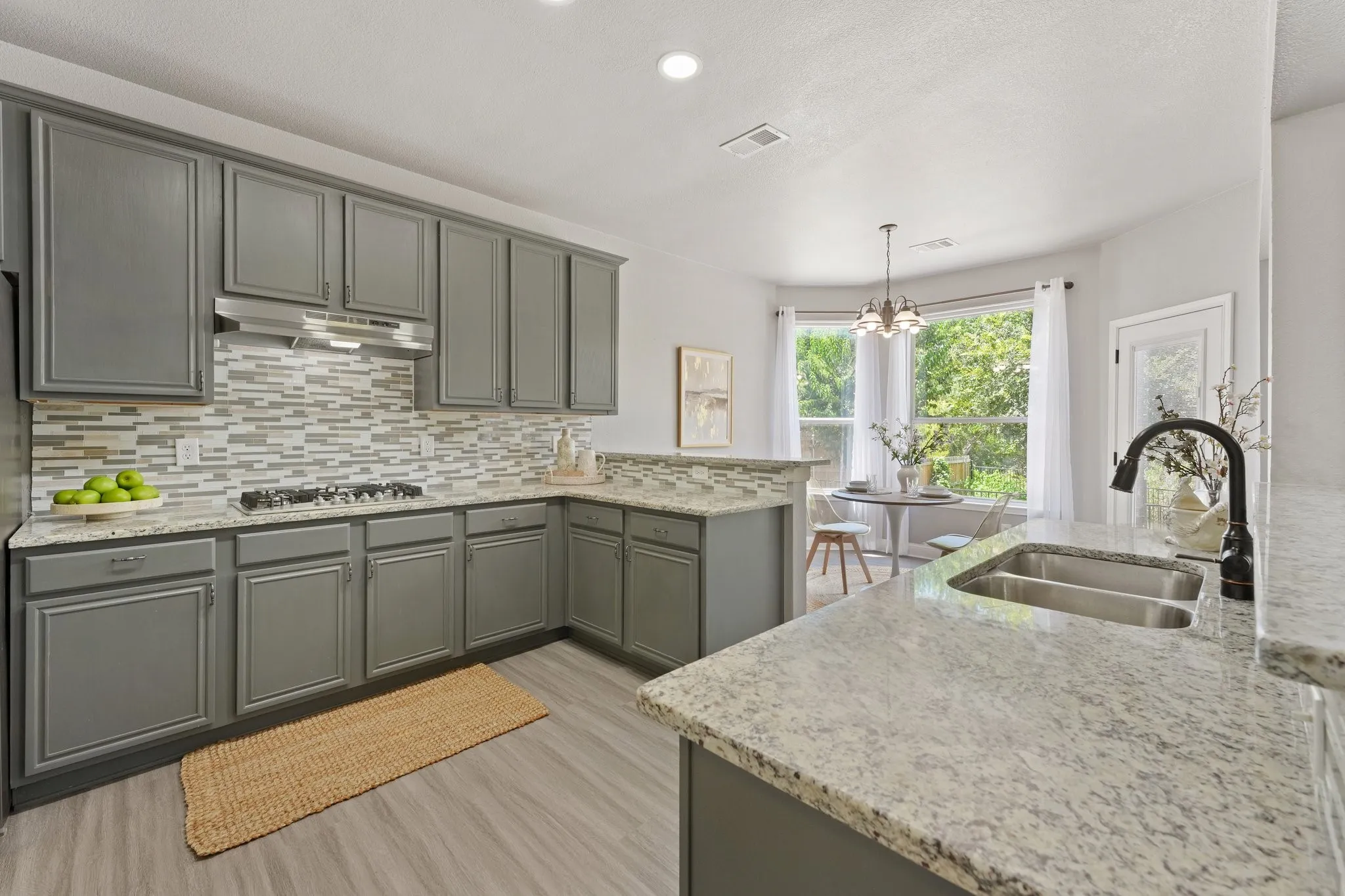 Kitchen featuring wood-finish flooring, gray cabinetry, light-toned countertops, and a full tile backsplash