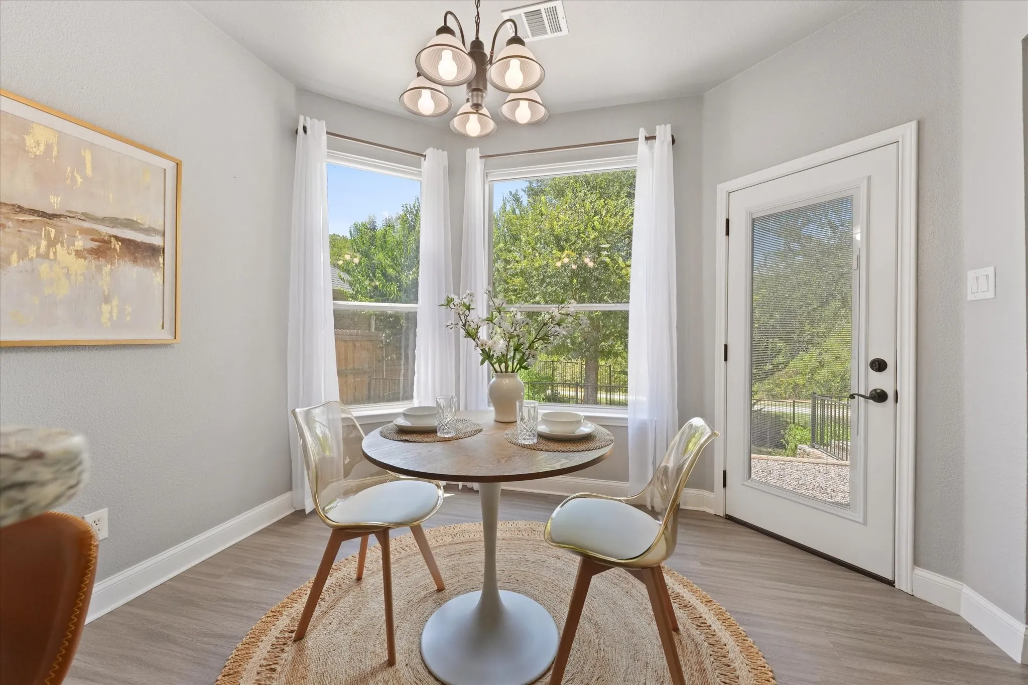 Bay window with multiple panes, full-light exterior door, wood-finish flooring, and a chandelier lighting fixture