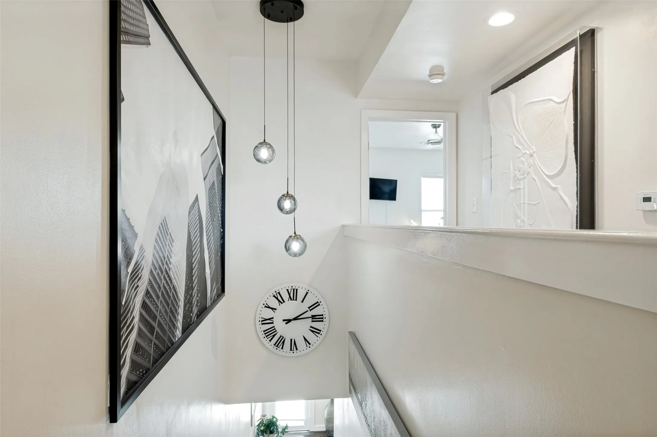 Recessed lighting, contemporary pendant light fixture, white painted walls, and built-in wall art