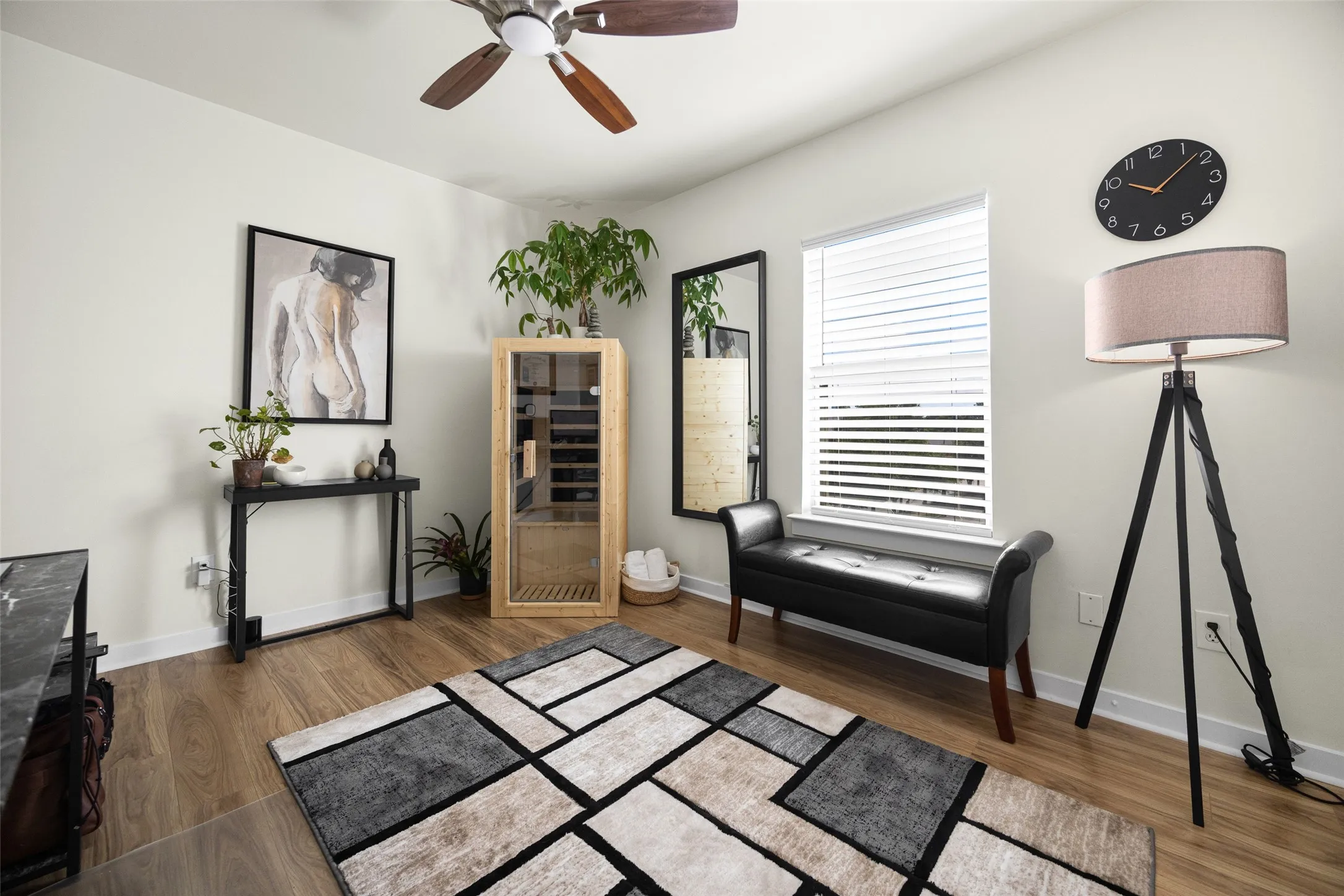 Spacious room with wood-finish flooring, a ceiling fan, and a large window with horizontal blinds