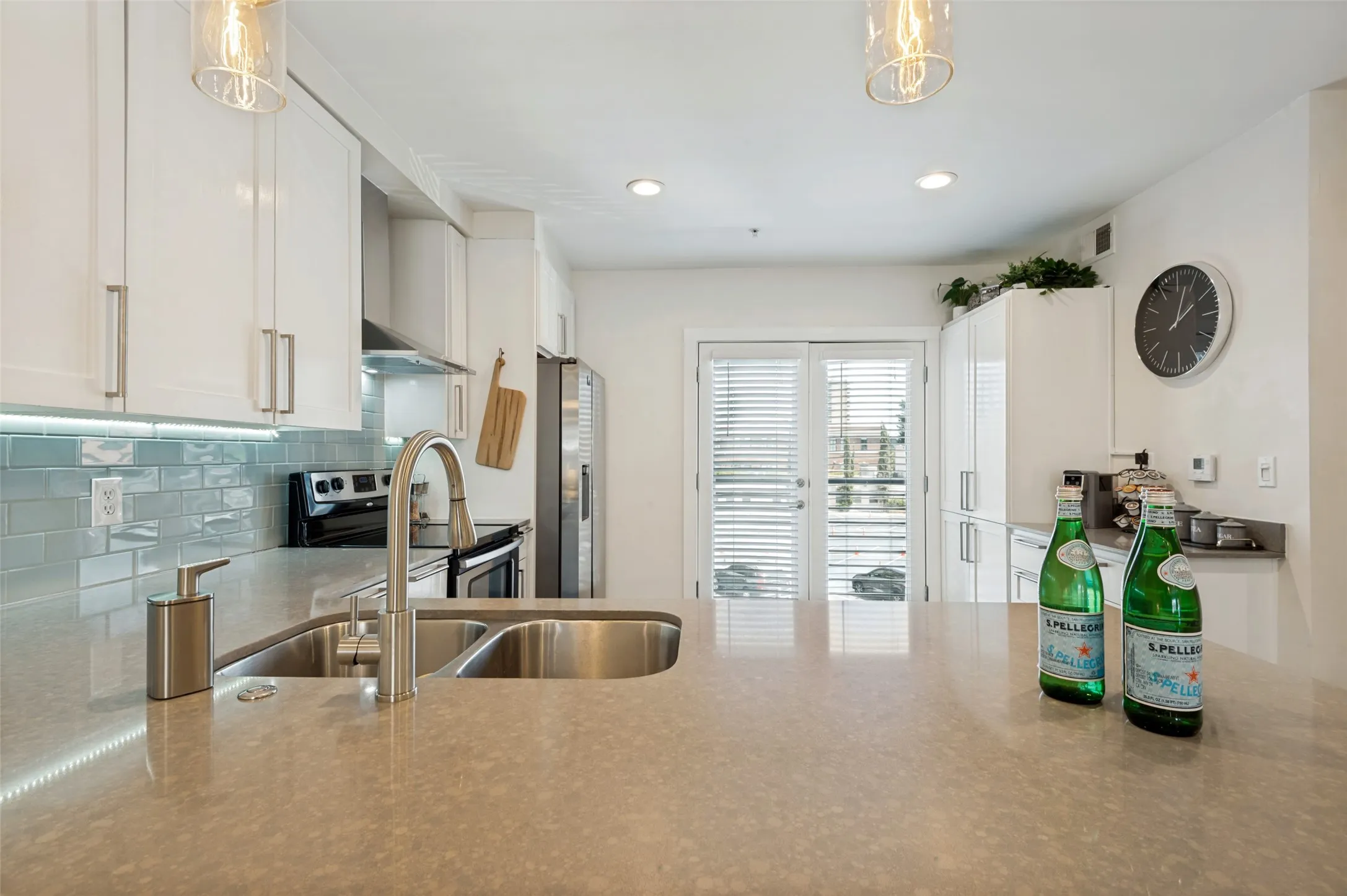 Kitchen featuring a double stainless steel sink, a gray countertop, white cabinetry, a light blue subway tile backsplash, and stainless steel appliances