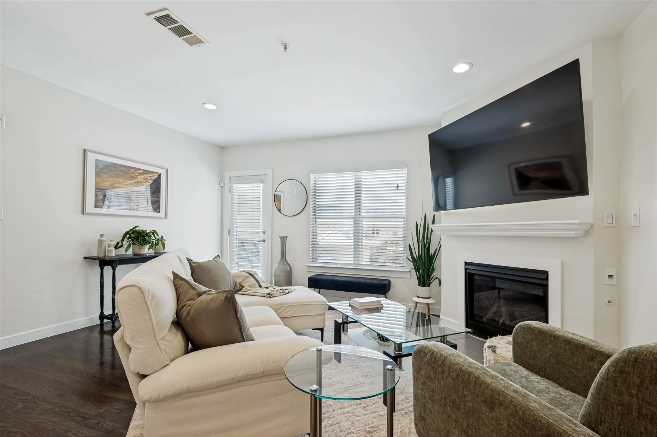Living area with dark wood-finish flooring, recessed lighting, and a fireplace with a white mantel
