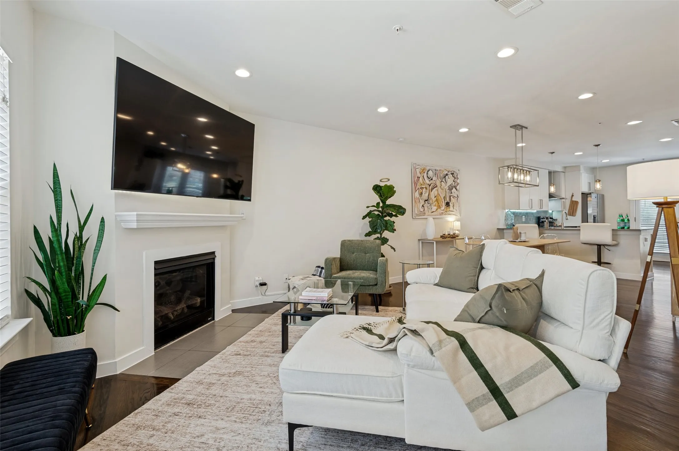 Recessed lighting, wood-finish flooring, white fireplace with mantle, and an open-concept layout