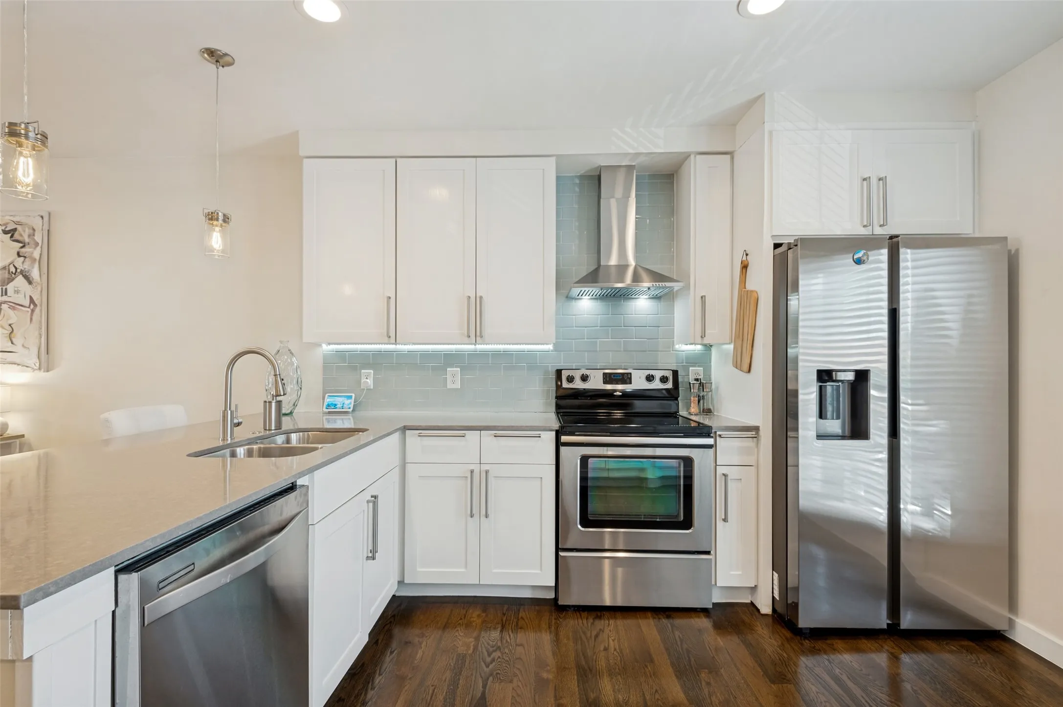 Modern kitchen featuring white cabinetry, stainless steel appliances, a tile backsplash, and dark wood-finish flooring