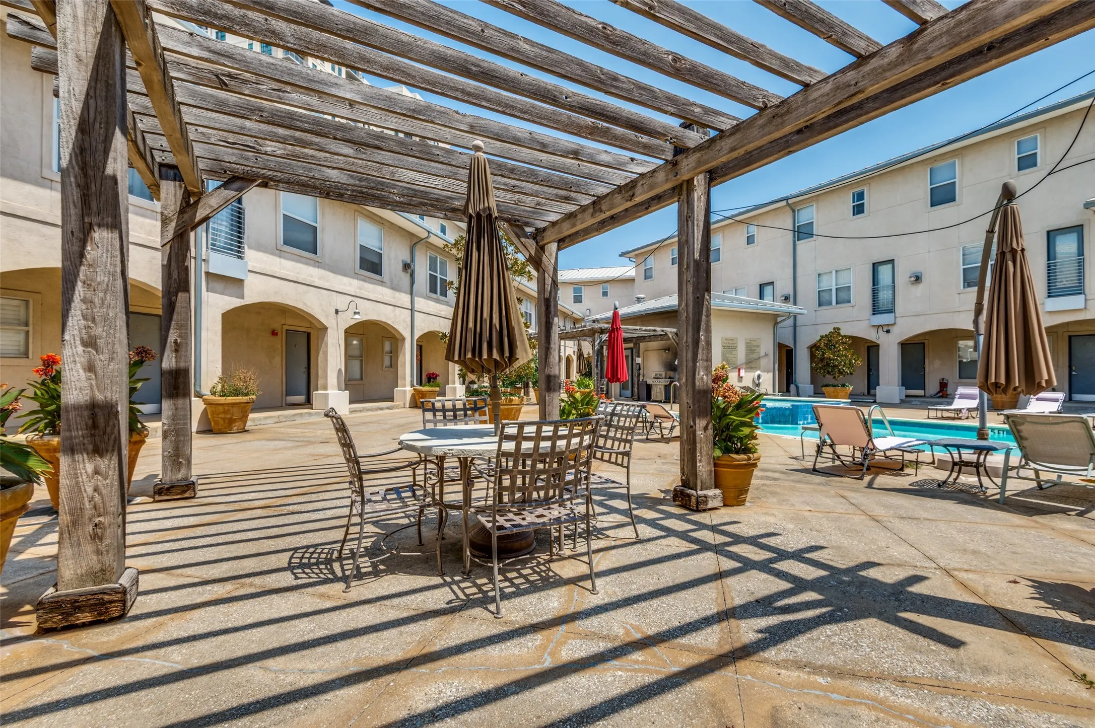 Expansive courtyard with a wood pergola, integrated swimming pool, and concrete patio