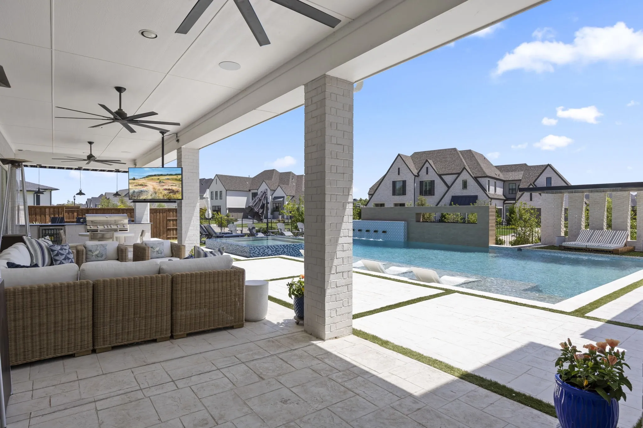 Multiple covered patios with outdoor kitchen and sitting area with multiple slider and double doors into the home.