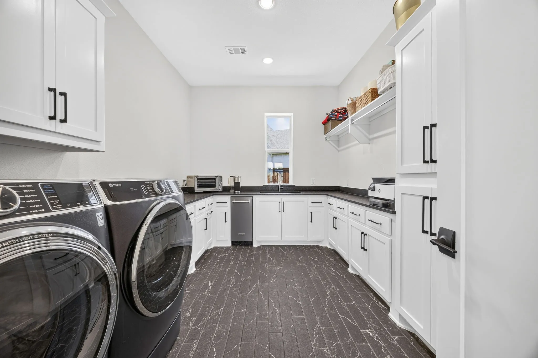 Huge laundry room has tons of storage, including a pass through laundry shoot to the primary closet. Also features an ice maker.