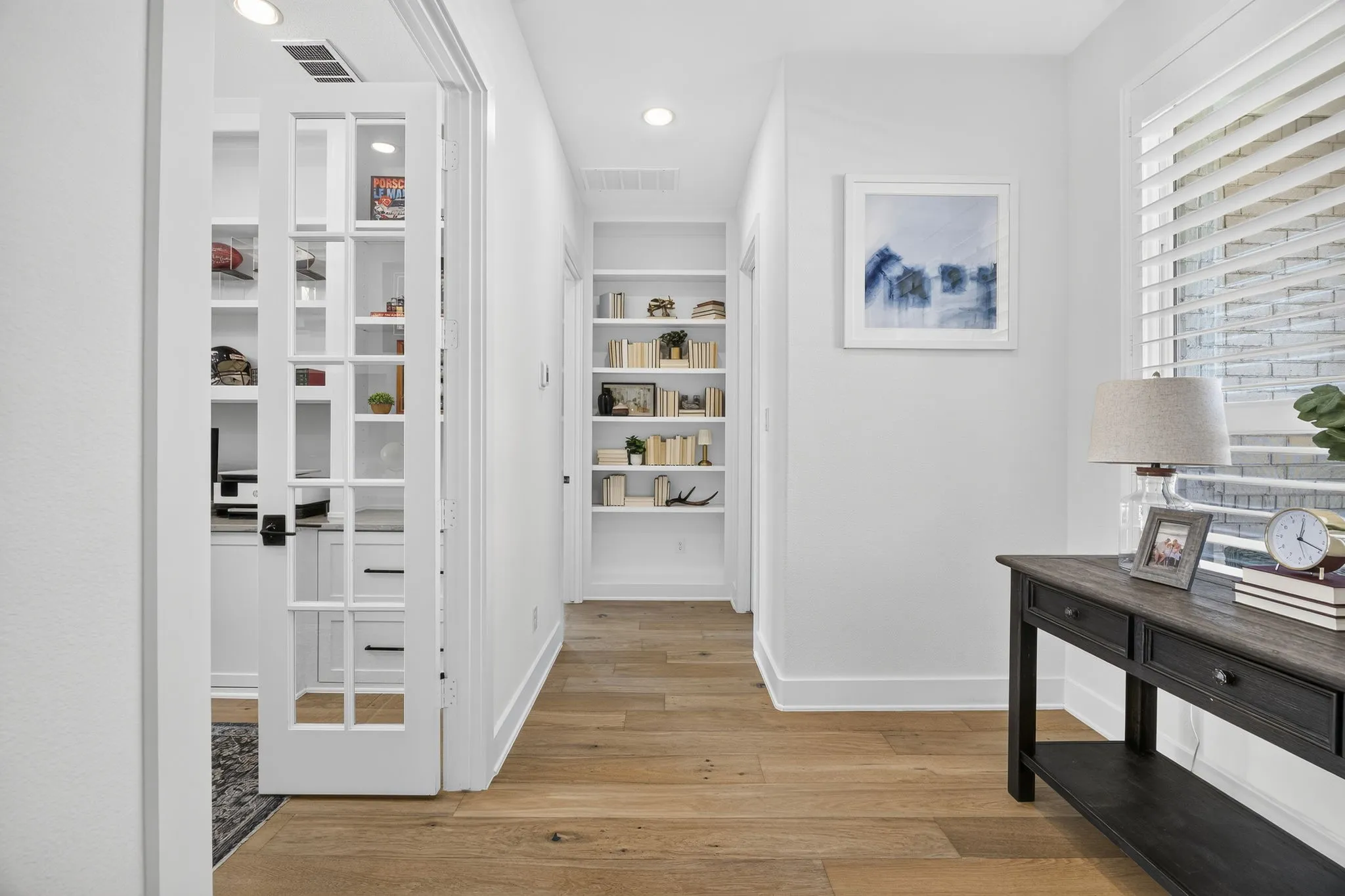 Hallway from the right of the entry leads to the office, downstairs guest suite and half bath.