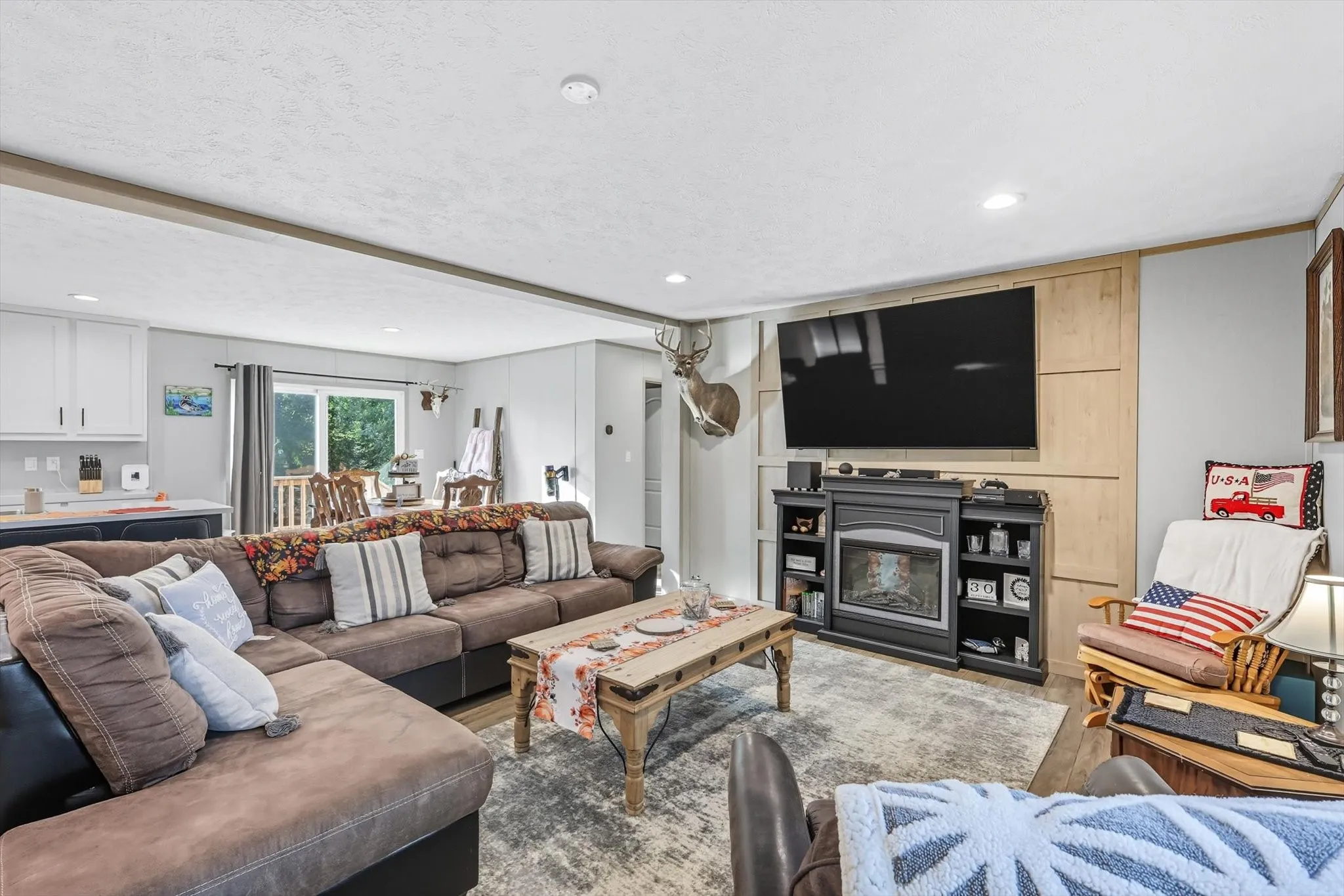 Living room featuring recessed lighting, a glass covered fireplace, wood finished floors, and a textured ceiling