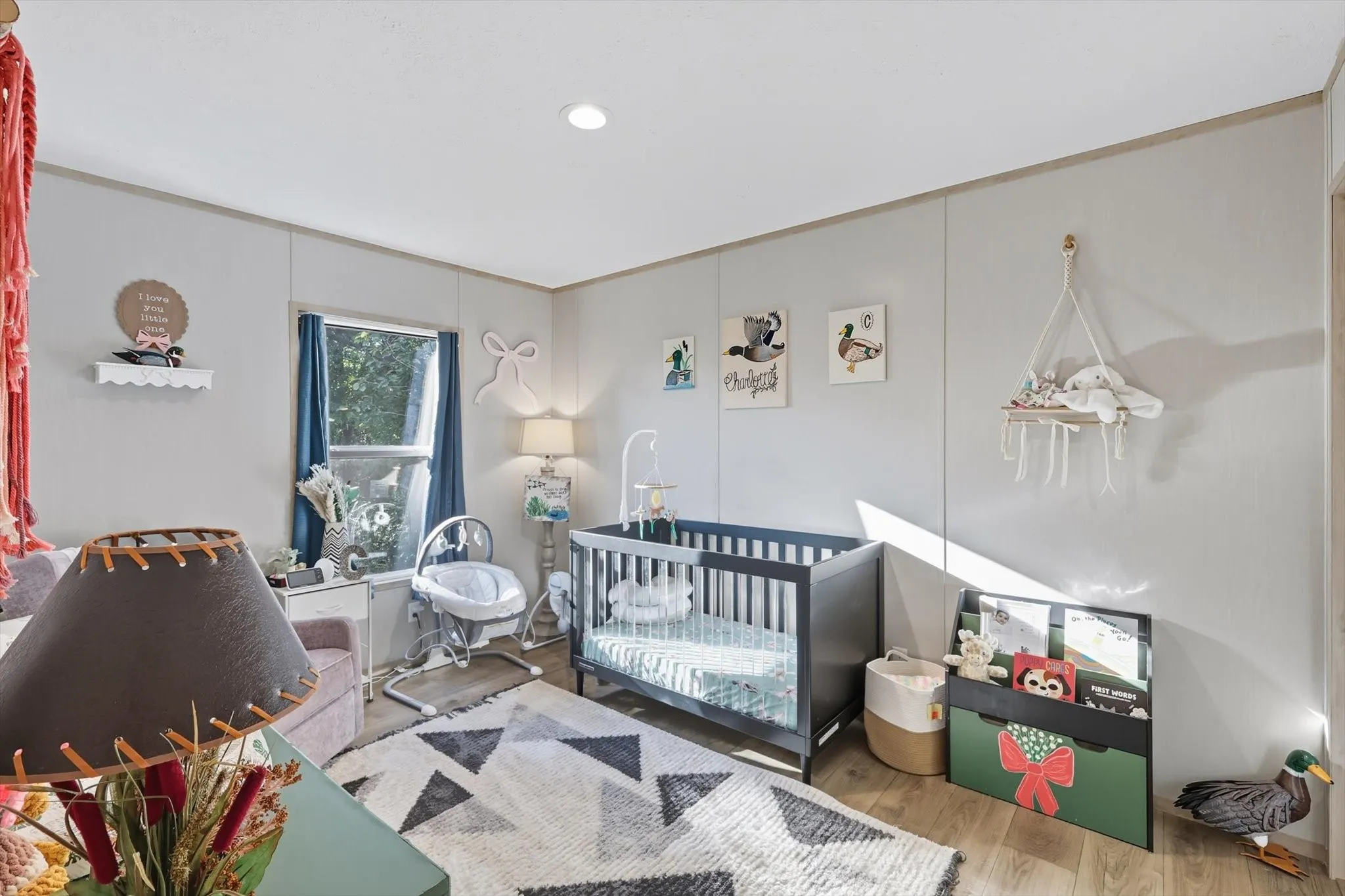 Bedroom with wood finished floors, a crib, and recessed lighting