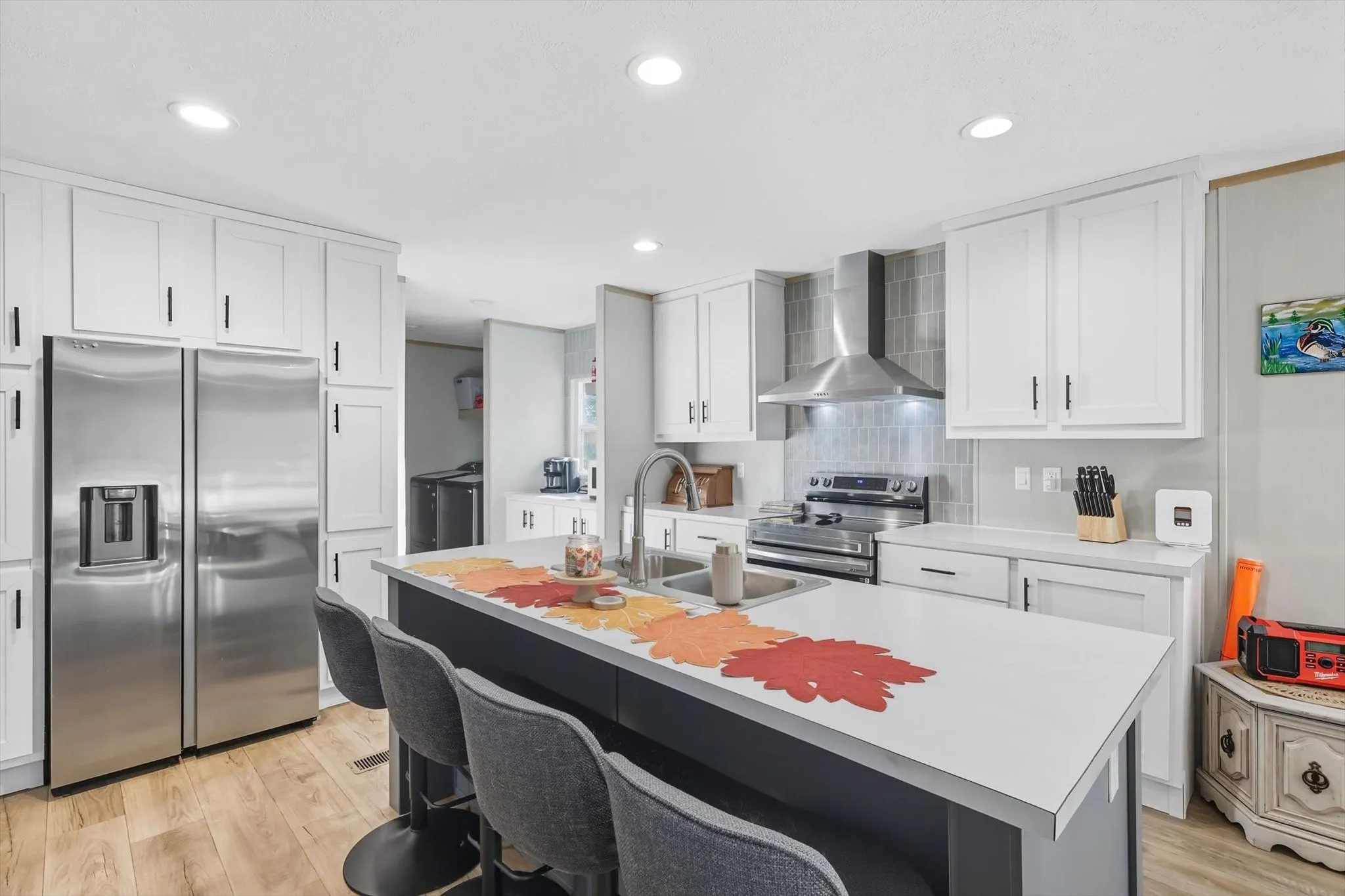 Kitchen with stainless steel appliances, light countertops, a breakfast bar, white cabinetry, and recessed lighting
