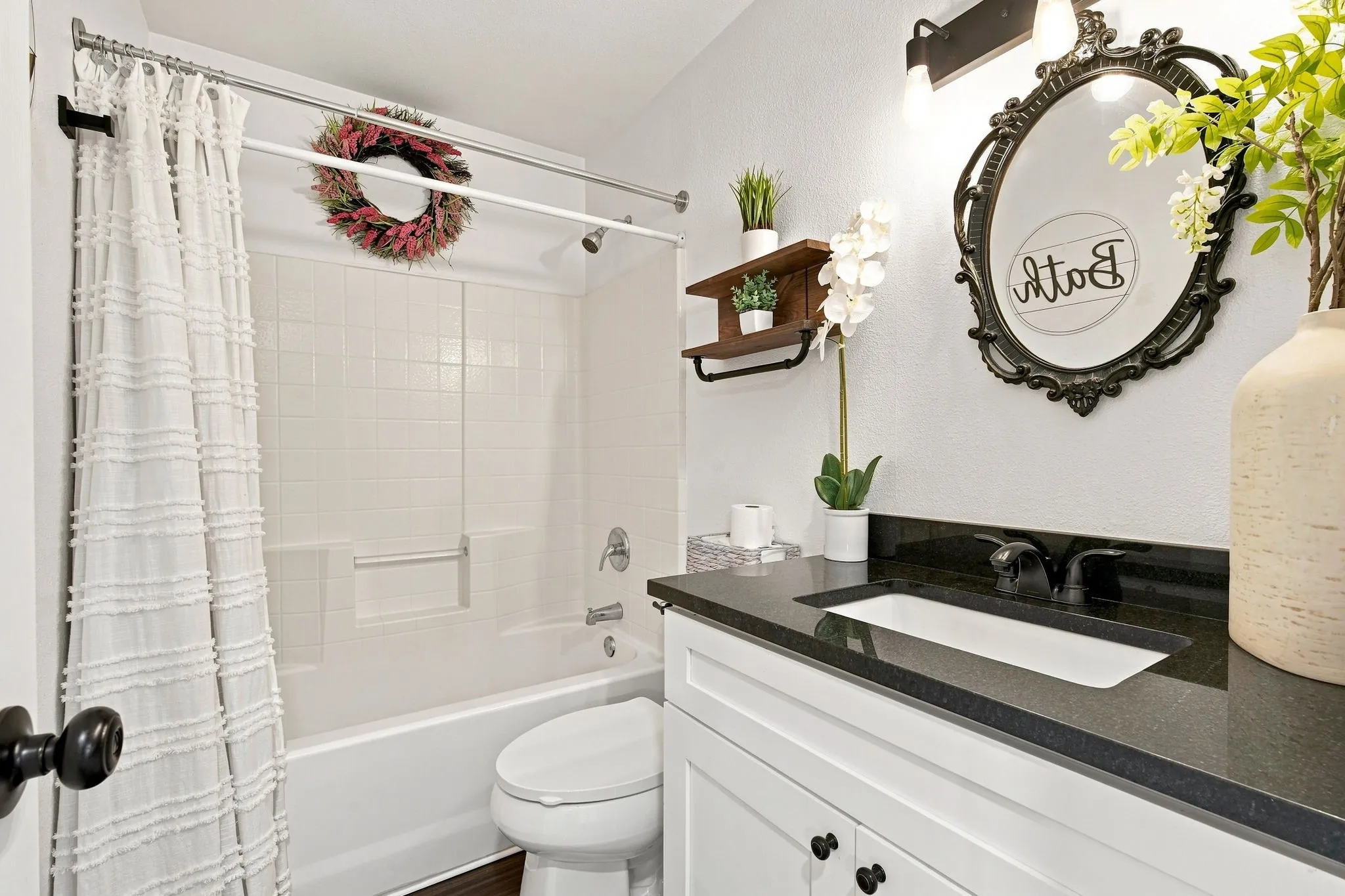 Bright second bath with a crisp white vanity and black hardware.