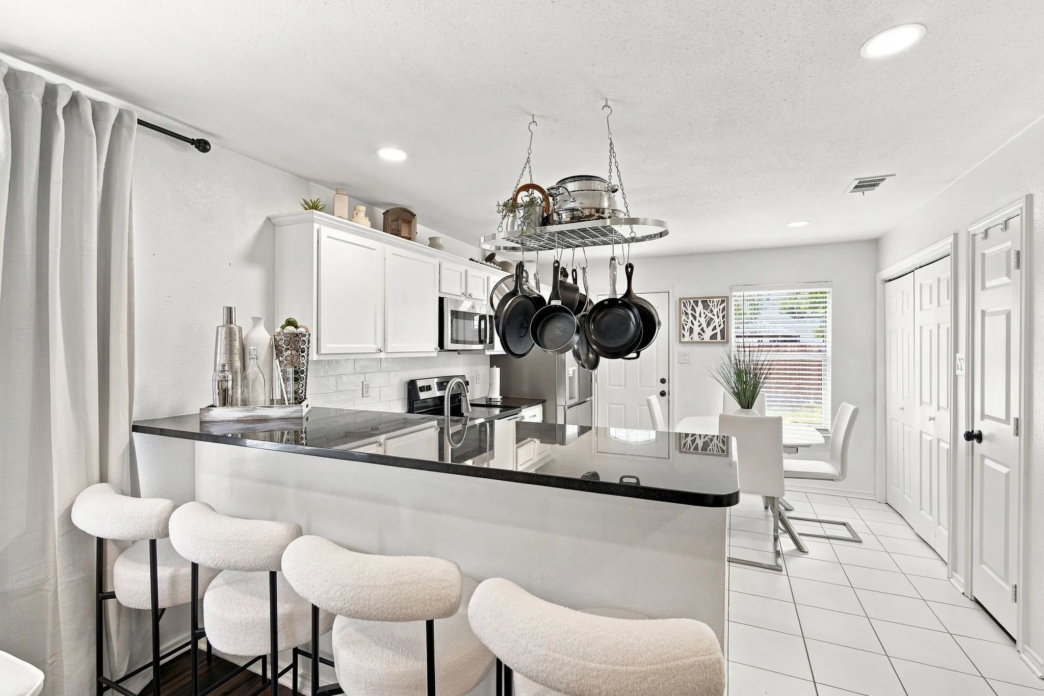 Crisp white cabinetry, stainless appliances, and a stylish pot rack create a kitchen that’s both functional and fun to cook in.