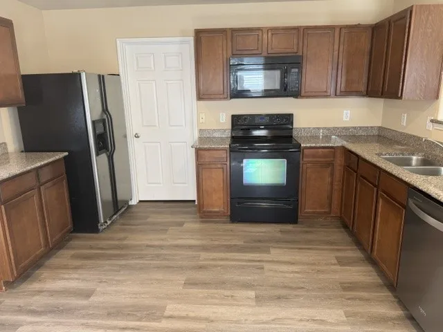 Kitchen featuring wood-finish flooring, dark wood cabinetry, light-toned countertops, and a double basin stainless steel sink