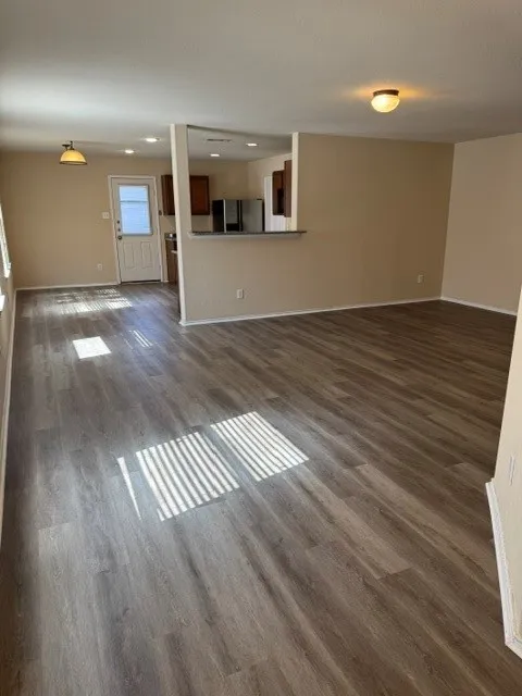 Open-concept living space with wood-finish flooring, neutral wall tones, and recessed lighting