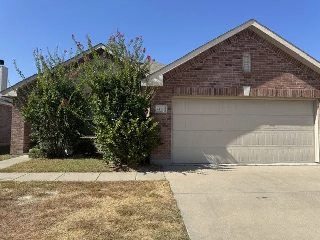 Brick exterior with a peaked roofline, attached garage, and mature shrubbery