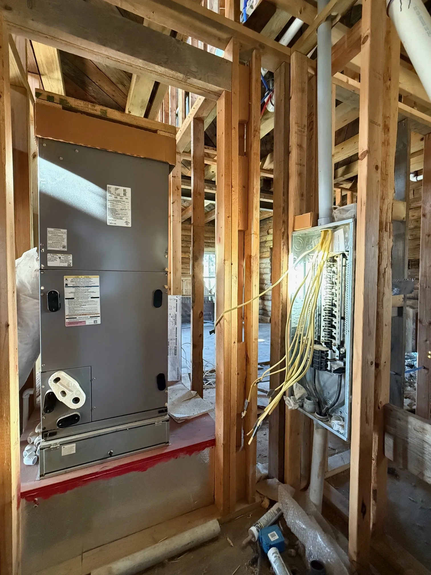 New HVAC system installation featuring an electrical panel and visible wiring within unfinished framing