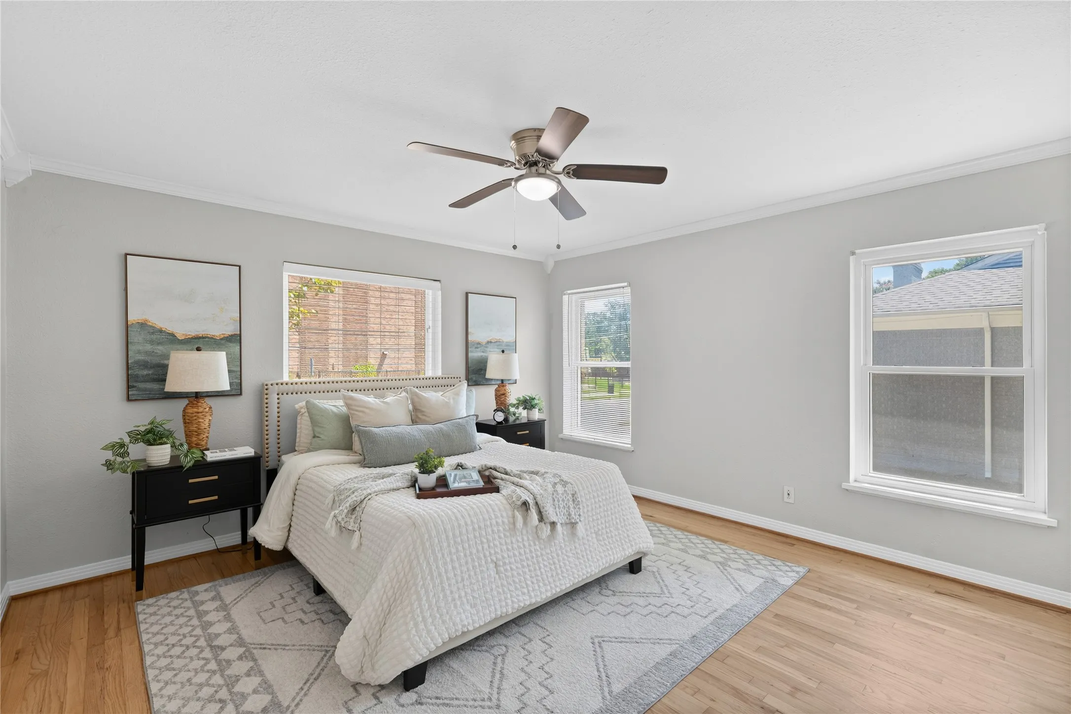 Hardwood-finish flooring, multiple windows, crown molding, and a ceiling fan with integrated lighting