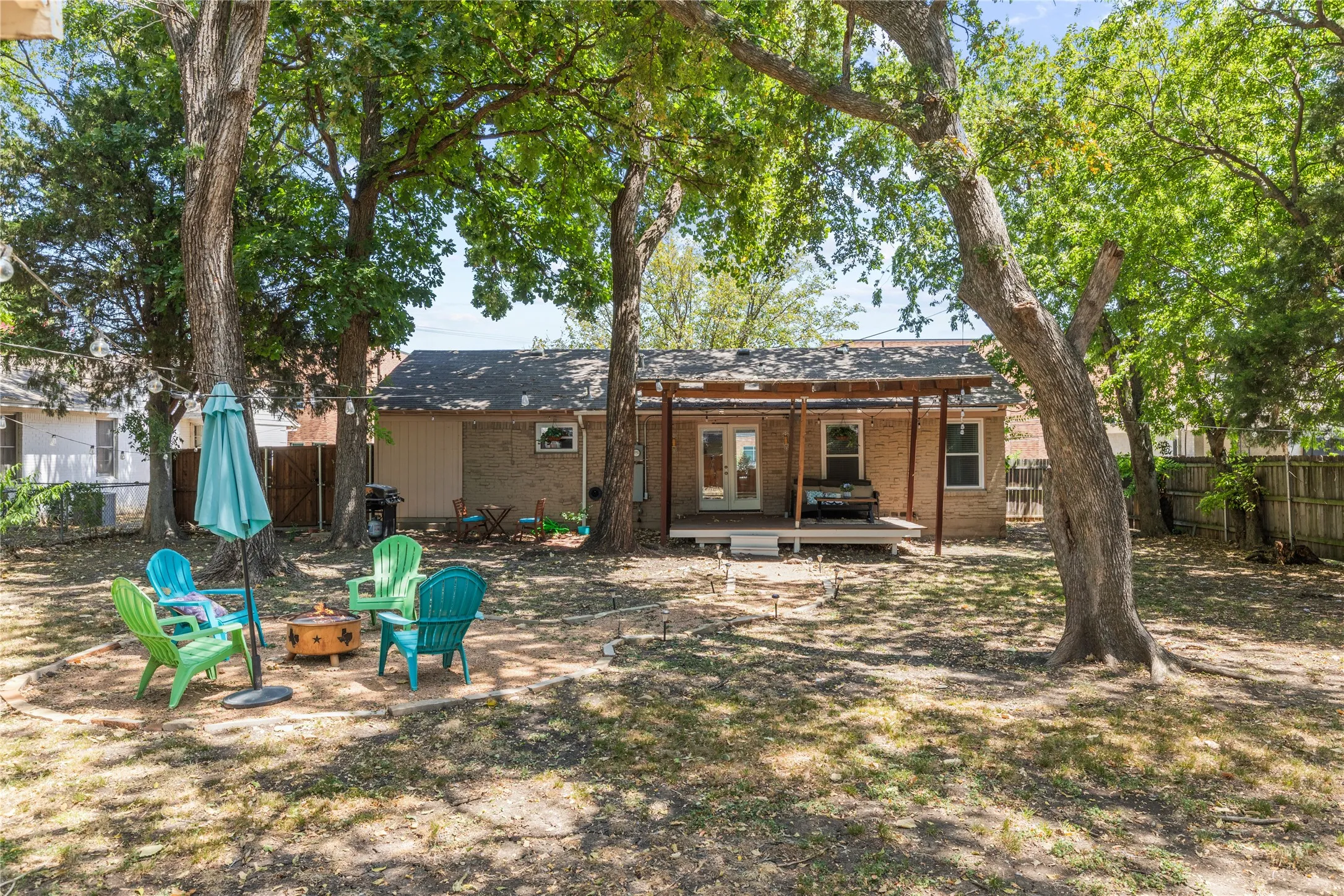 Expansive backyard featuring mature trees, a wooden deck, and a covered patio structure