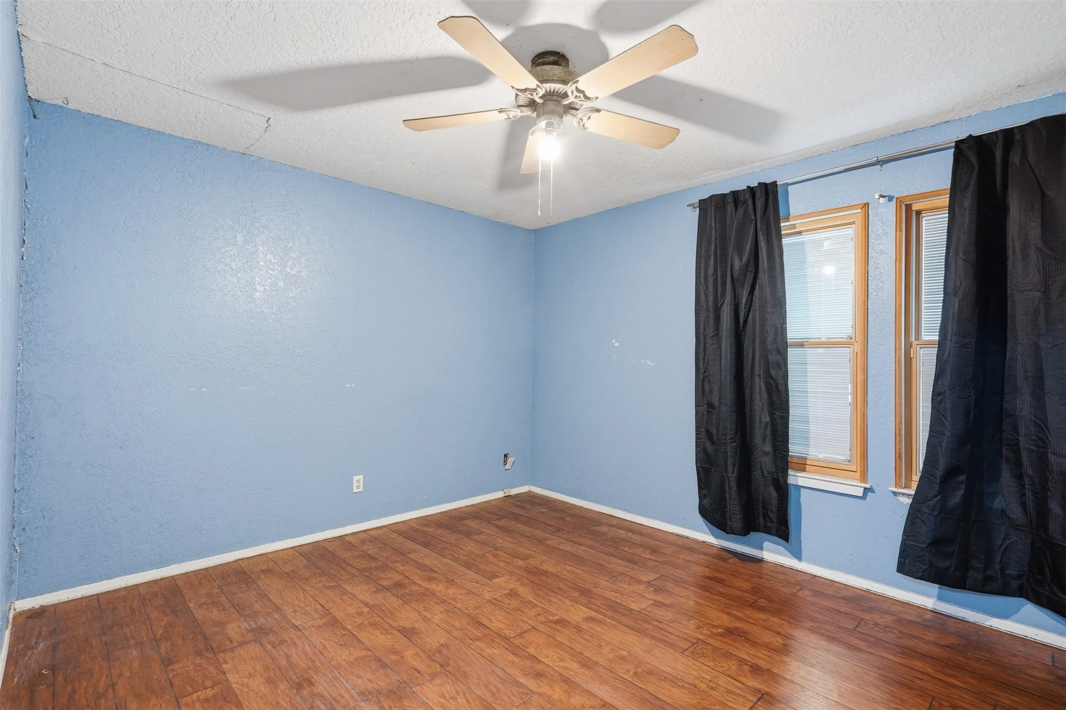 Wood-finish flooring, ceiling fan with integrated lighting, and two windows