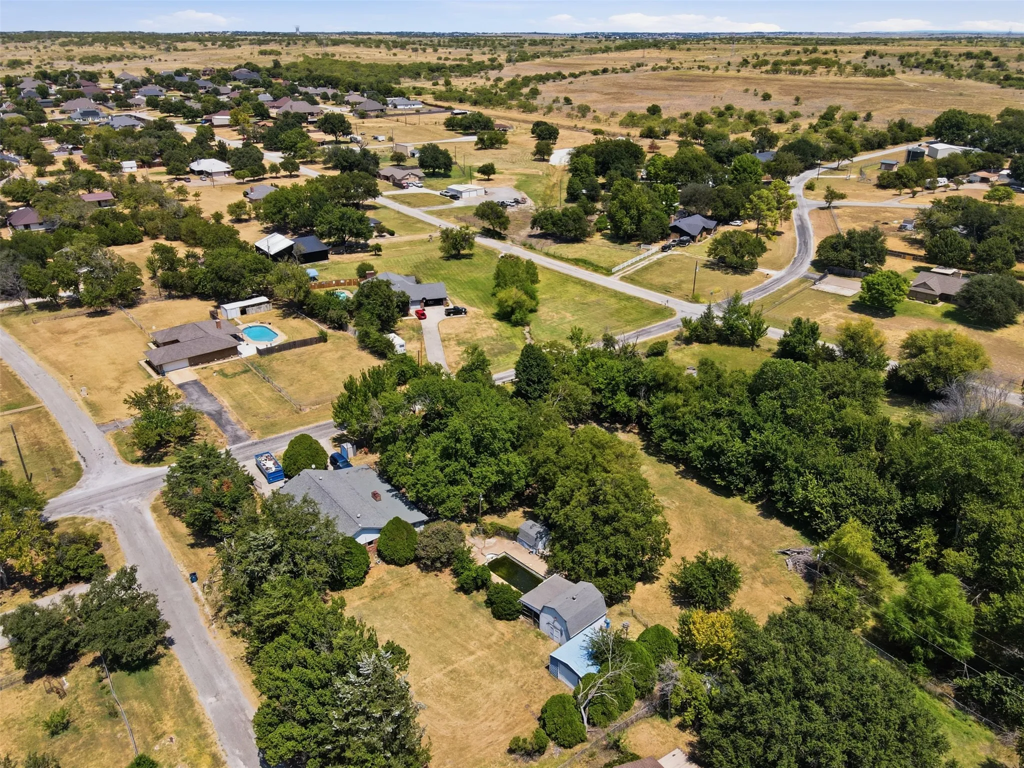 Residential property featuring a spacious lot, mature trees, and an in-ground swimming pool