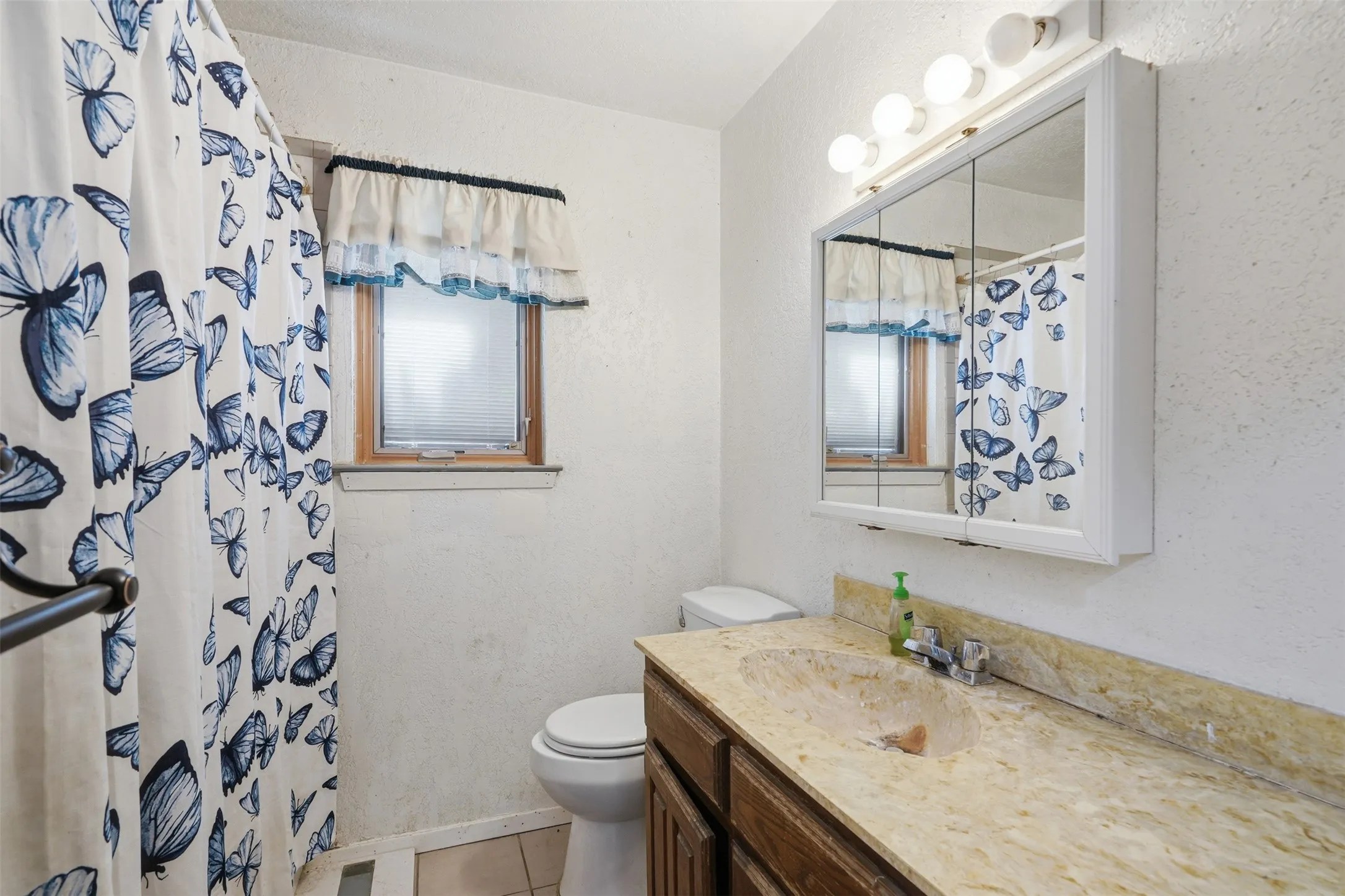 Single vanity with integrated sink, wood-finish cabinetry, wall-mounted medicine cabinet, and overhead lighting fixture