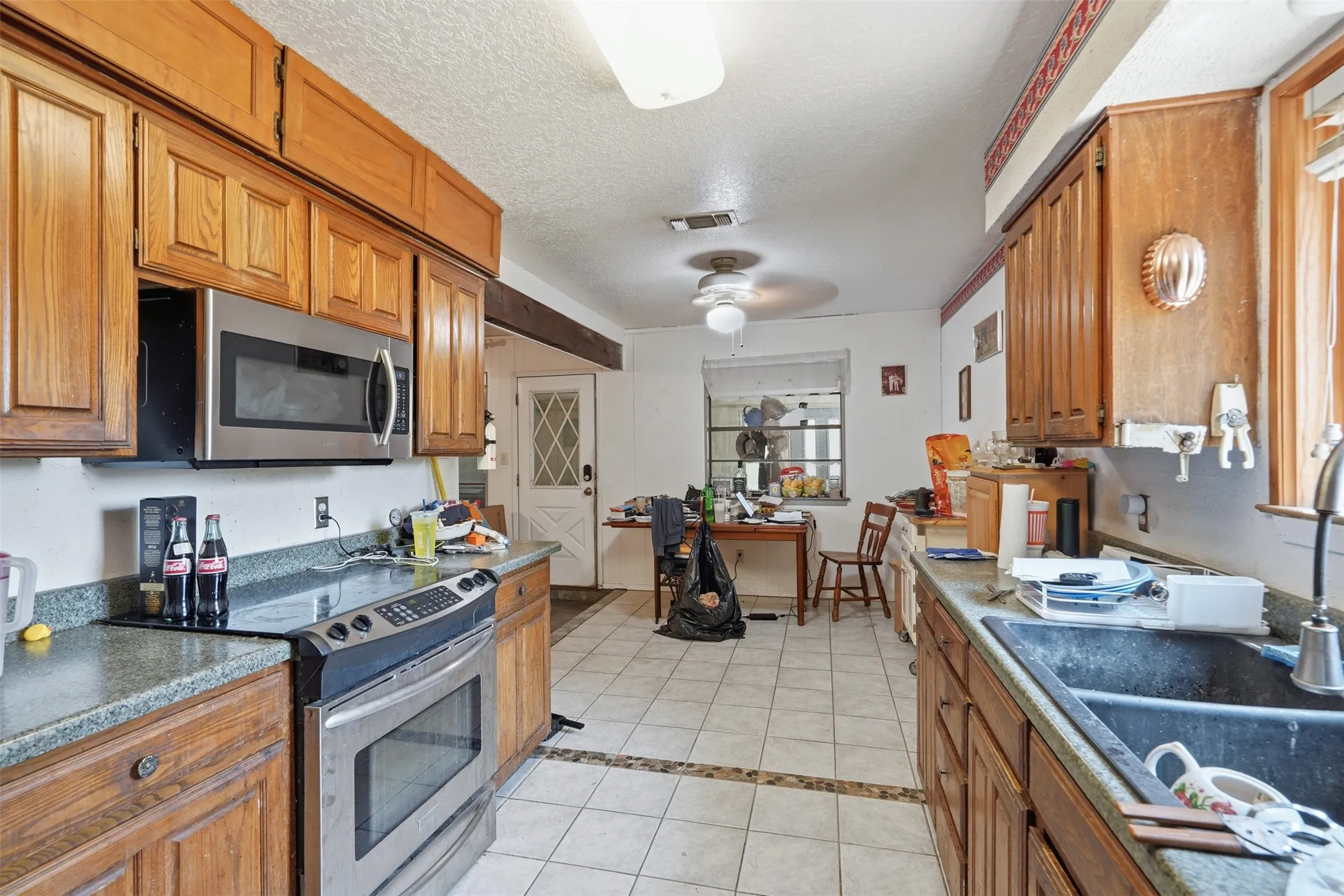 Kitchen featuring wood cabinetry, stainless steel microwave, stainless steel range, and tile flooring with decorative inlay