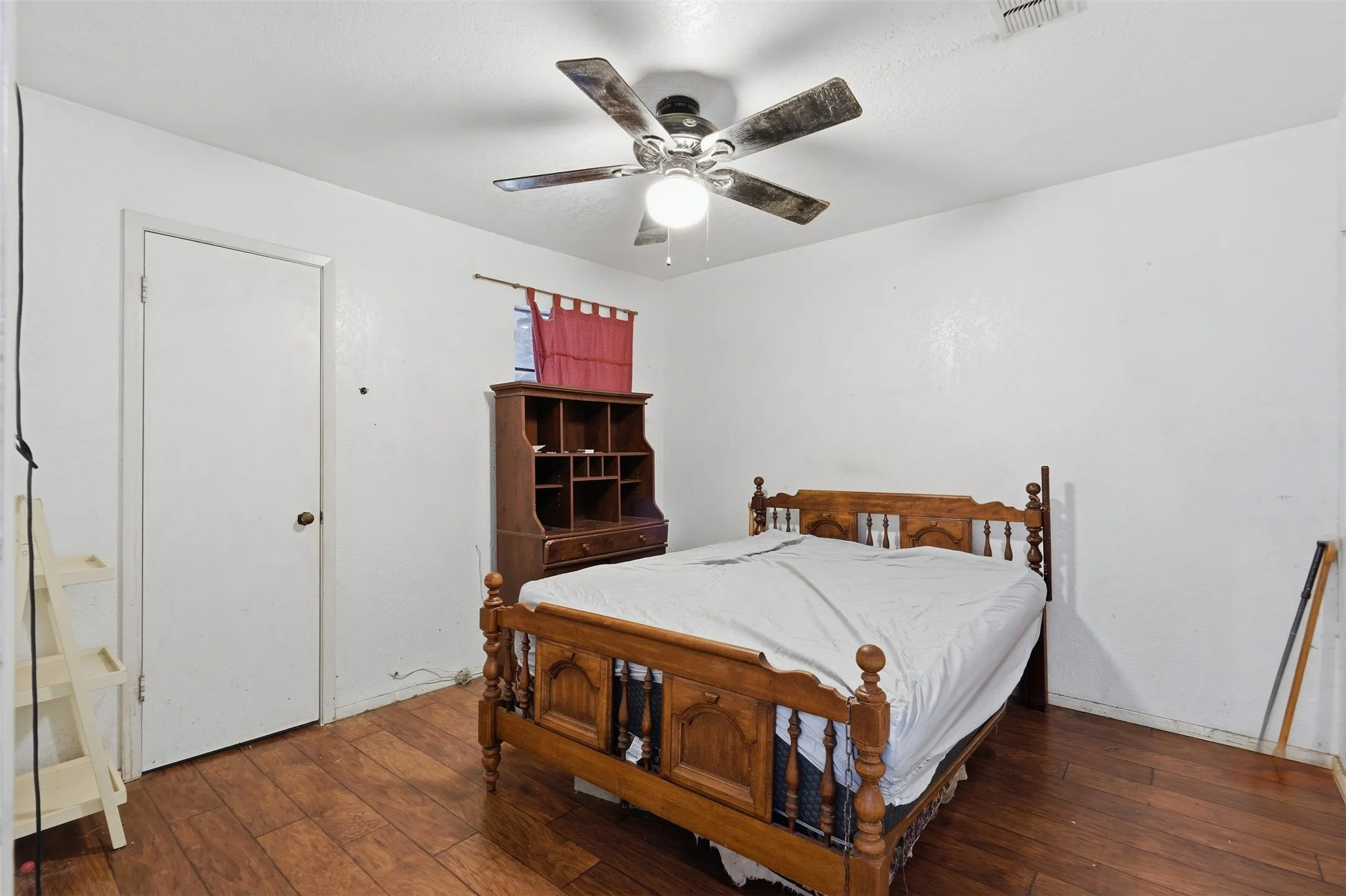 Wood-finish flooring with white walls and a ceiling fan