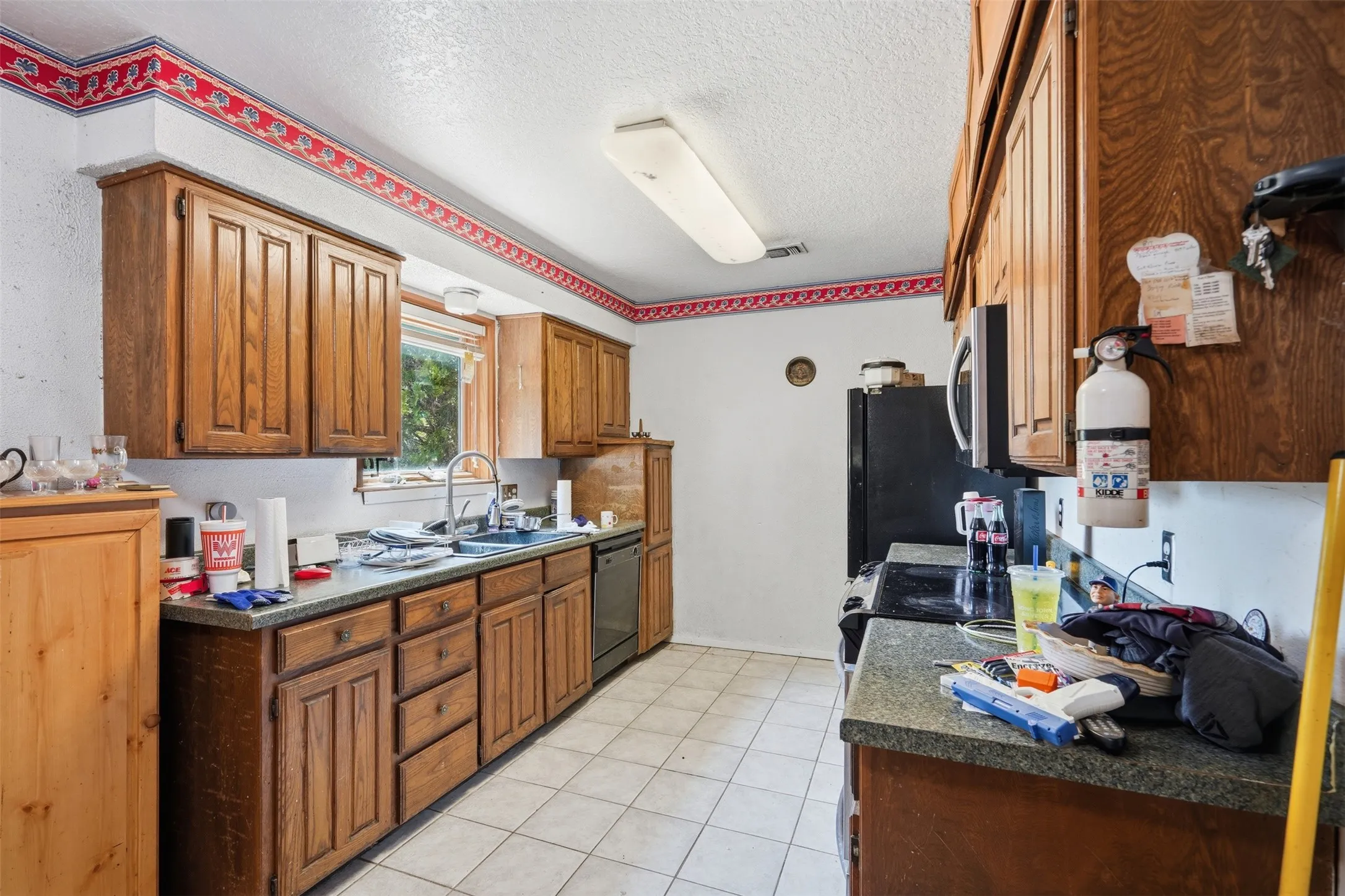 Galley kitchen featuring wood cabinetry, stone-finish countertops, and tile flooring