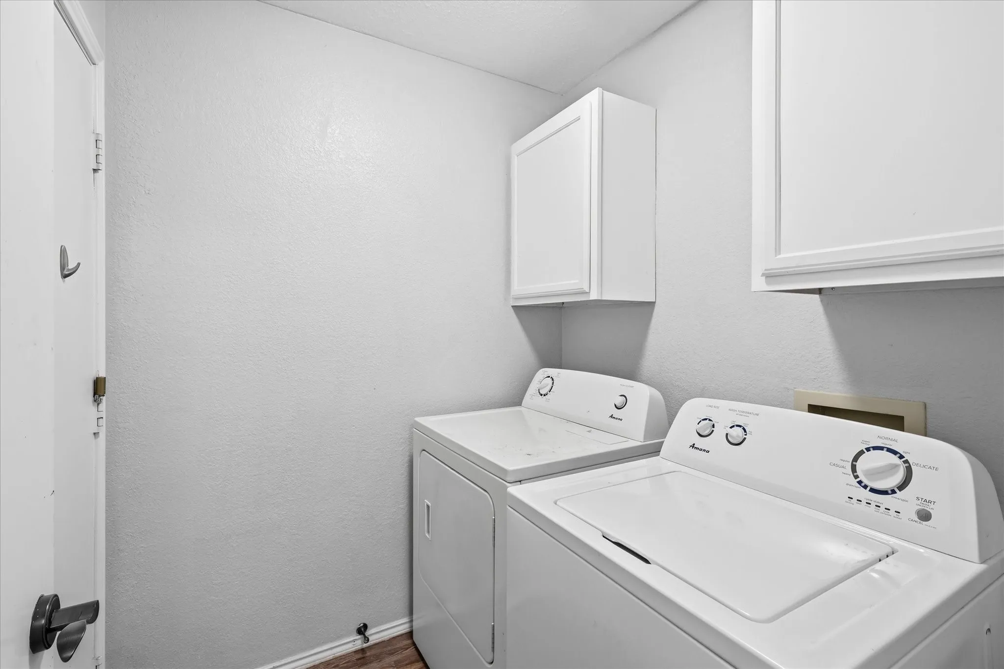 Laundry room with washer dryer hookups and extra cabinets for storage.