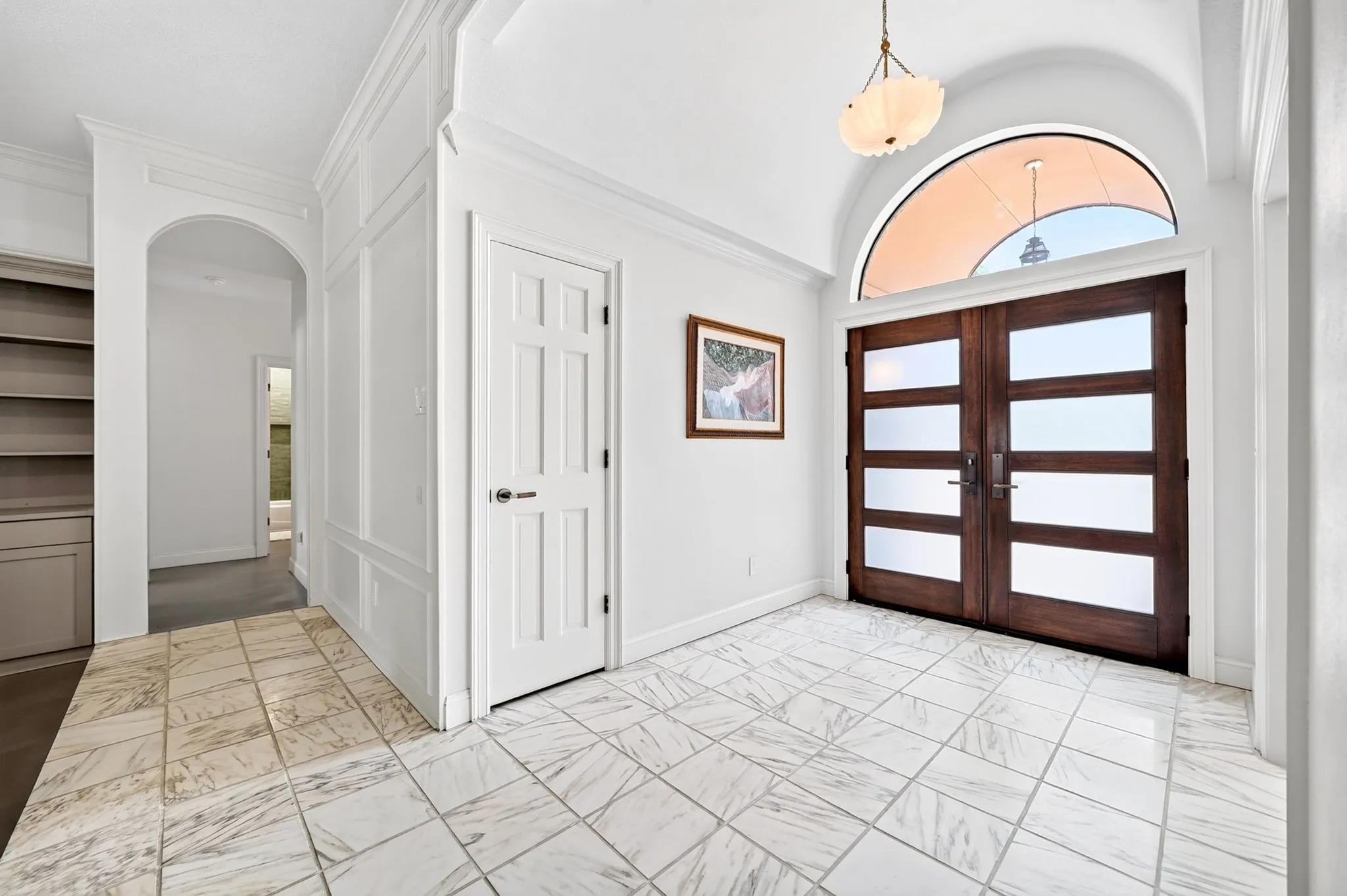 Double wood doors with frosted glass panels and an arched transom window