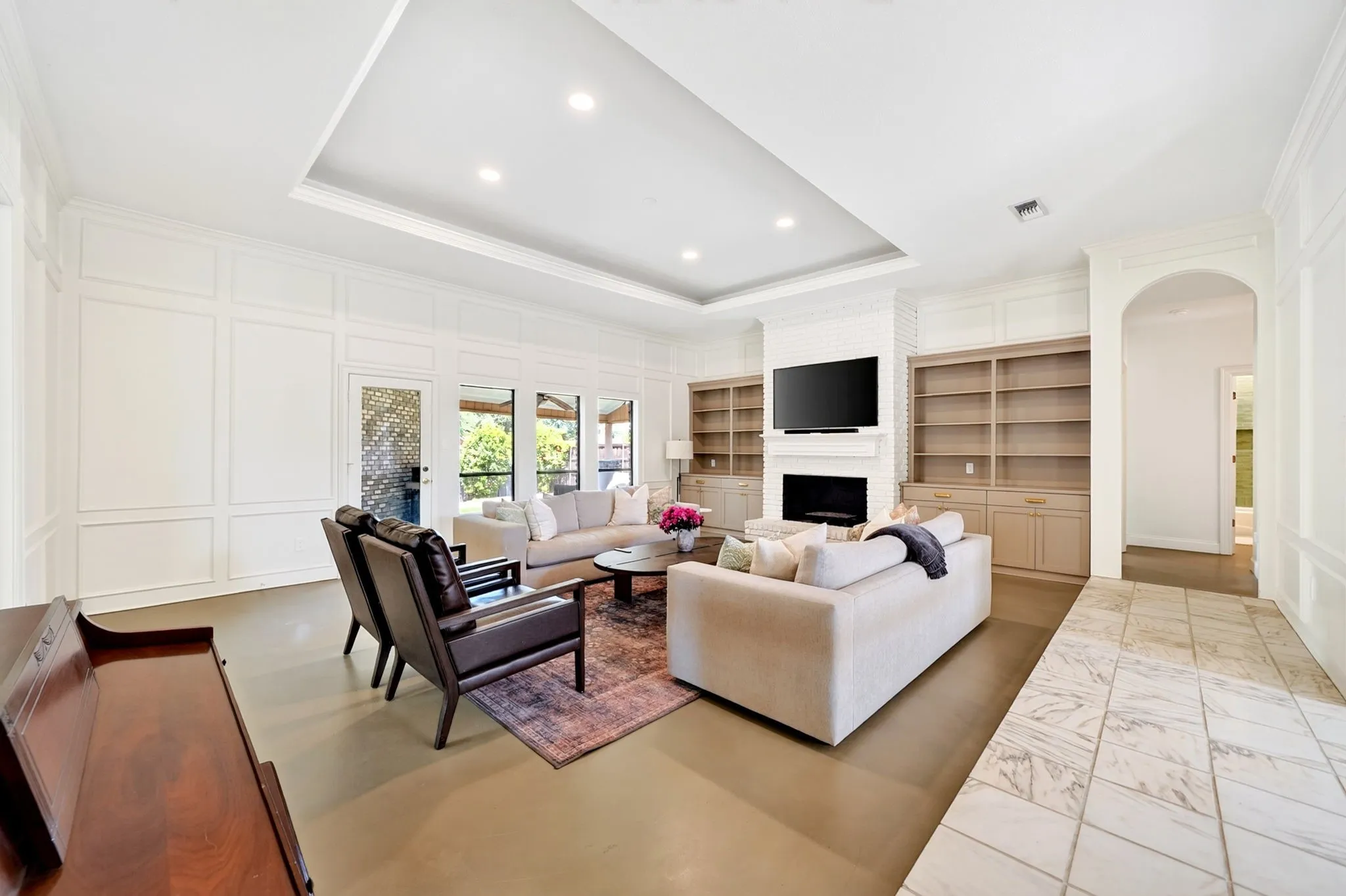 Spacious living area featuring a tray ceiling, recessed lighting, built-in shelving, a fireplace, and large windows