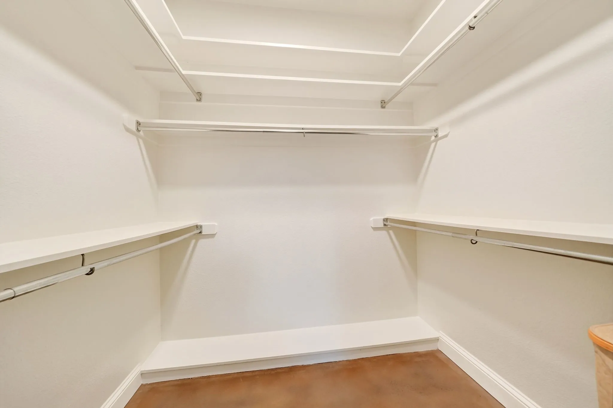 Walk-in closet with multiple white shelving units and hanging rods