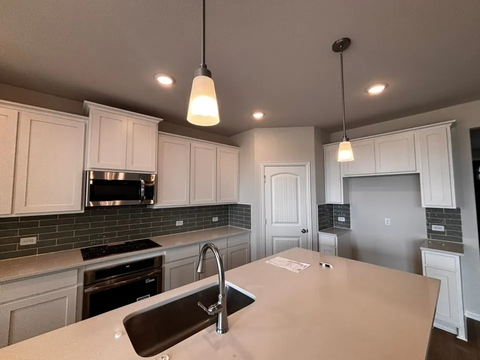 White cabinetry, solid surface countertops, stainless steel appliances, subway tile backsplash, and recessed lighting