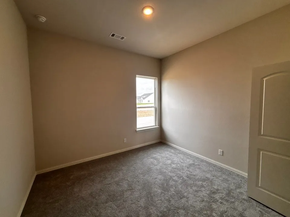 Carpeted room with a single window, a flush mount ceiling light, and a paneled door
