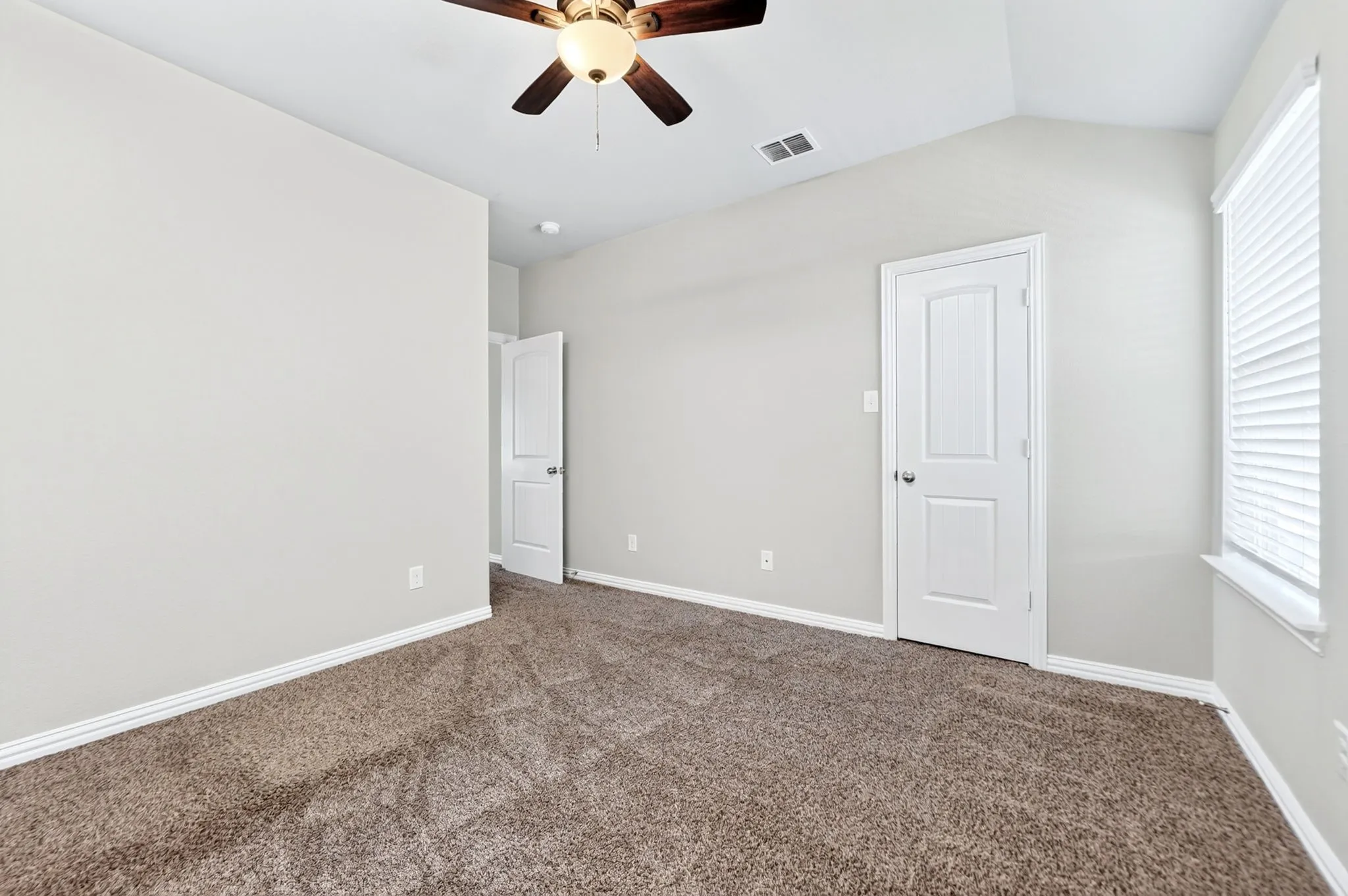 Vaulted ceiling with an attached ceiling fan, carpeted flooring, and window with blinds