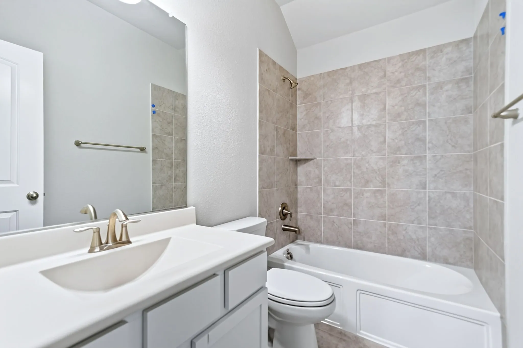 White vanity with integrated sink, brushed nickel faucet, full-width mirror, tile-surround bathtub, and built-in shelving